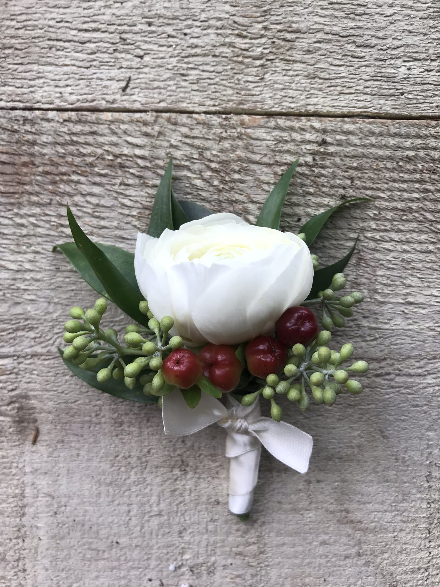 Ranunculus Boutonniere - Ranunculus Boutonniere with variety of greenery, hypericum berries wrapped in satin ribbon. Please specify ribbon color. Greenery and filler may vary based on season and availability.  