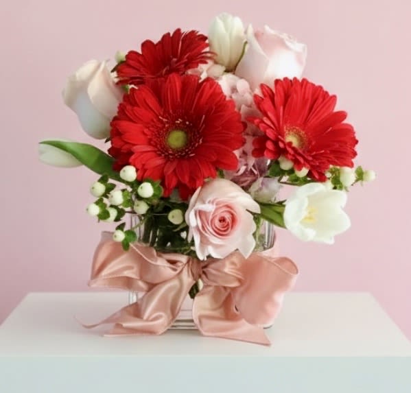 XOXO - A Sweet little bouquet of red gerbera daisies, pink roses, white tulips and hypericum with a pretty pink bow SUBSTITUTION OF EXACT FLOWERS MAY BE NECESSARY
