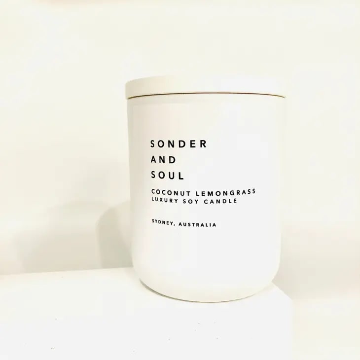 Sonder and Soul - Coconut Lemongrass Soy Candle - About this product   Have you ever been to an exotic island with a tropical climate that offers an exciting view of the beach and an array of fragrant tones? This is exactly what our Coconut Lemongrass Luxury Soy Candle smell like.   Bring the tropical island breeze and warmth to your space with our artisan luxury candle and take a vacation right in the comfort of your home.   Our Coconut Lemongrass is tarty and fruity and infused with a blend of pineapple, lemongrass, lime, peach, vanilla, sandalwood, and coconut.  It comes with a matte white jar with a white wooden lid making it a perfect decor for any room.  Crafted with love and passion, this lux candle is sure to make you feel calm and relaxed.