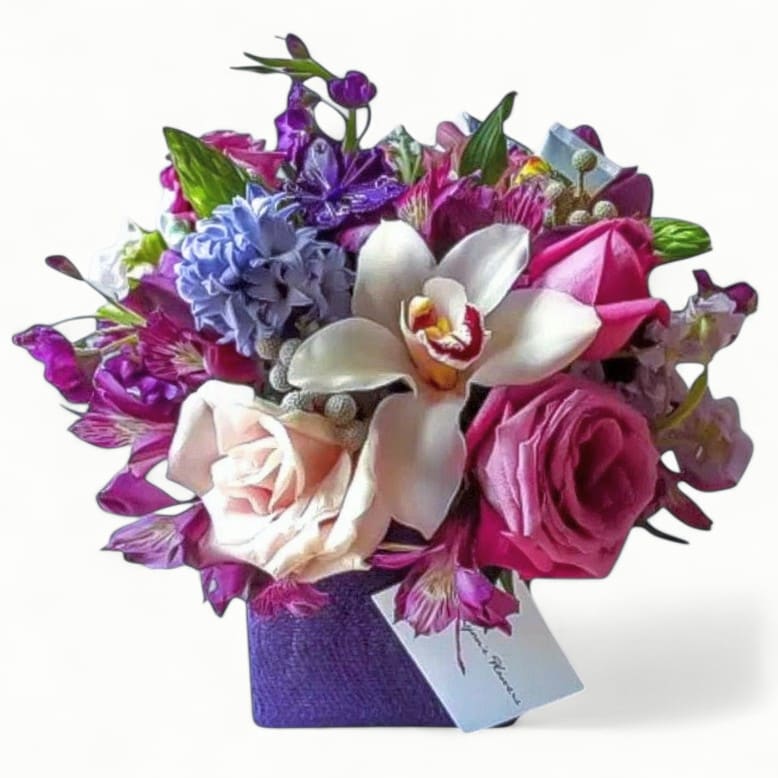 Lavender Birthday Designer's Choice - Roses orchids and more arranged in a modern glass cube style vase wrapped in purple jute ribbon. Beautiful. Perfect to send for every reason. All of my bouquets are always made extra special and unique each time. Send them happiness today.