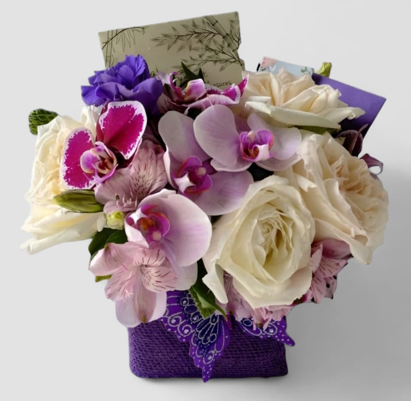 Purple Vanilla Bouquet Designer's Choice - Roses orchids and more arranged in a modern glass cube style vase wrapped in purple jute ribbon. Perfect to send for every occasion to make them smile. All of my bouquets are always made extra special and unique each and every time. Send them happiness.