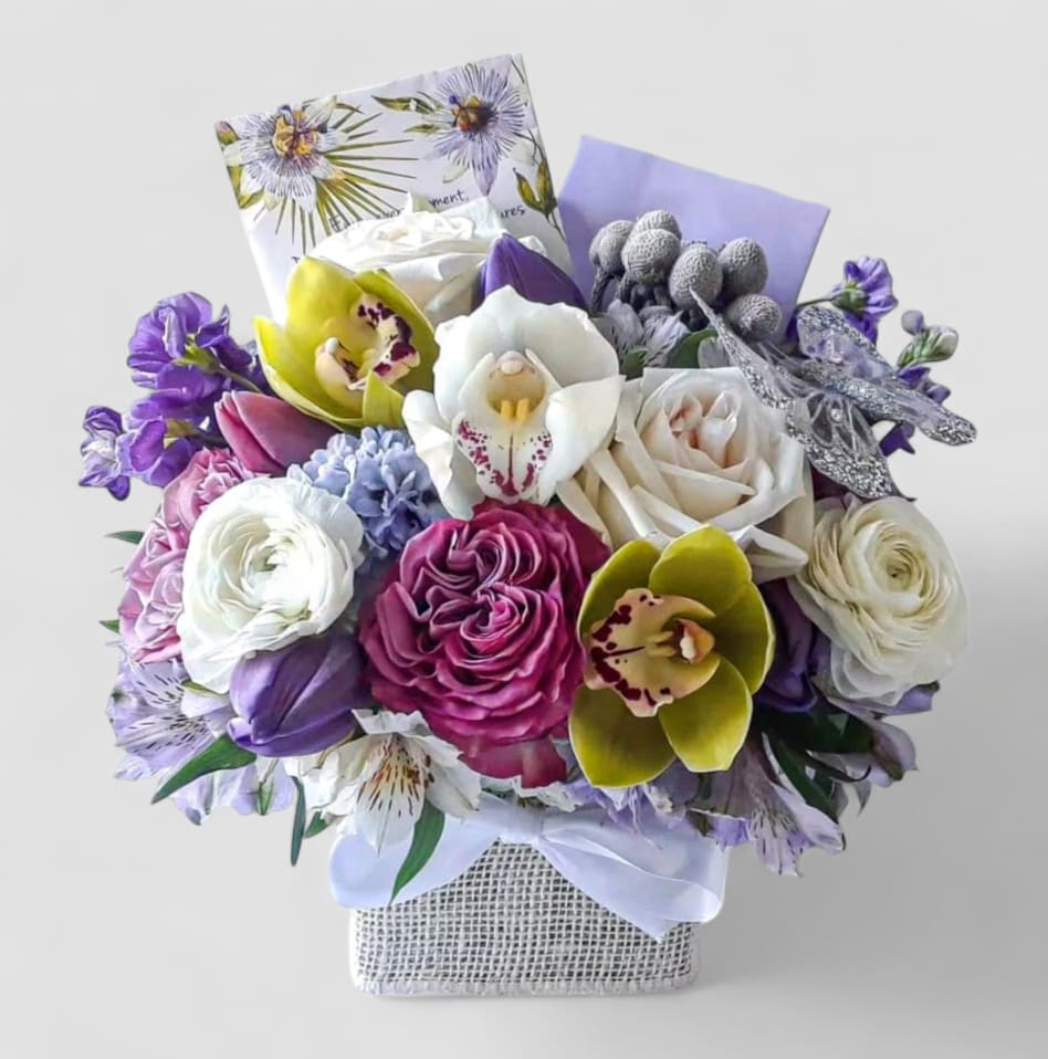 Happy Day Bouquet Designer's Choice - Designer's choice; made beautifully from my lavender and vanilla blossoms of the day roses orchids and more arranged in a modern glass cube style vase wrapped in vanilla jute ribbon. Gorgeous and perfect to send today to show them how much you care. All of my bouquets are always made extra special and unique each and every time. Send them happiness.