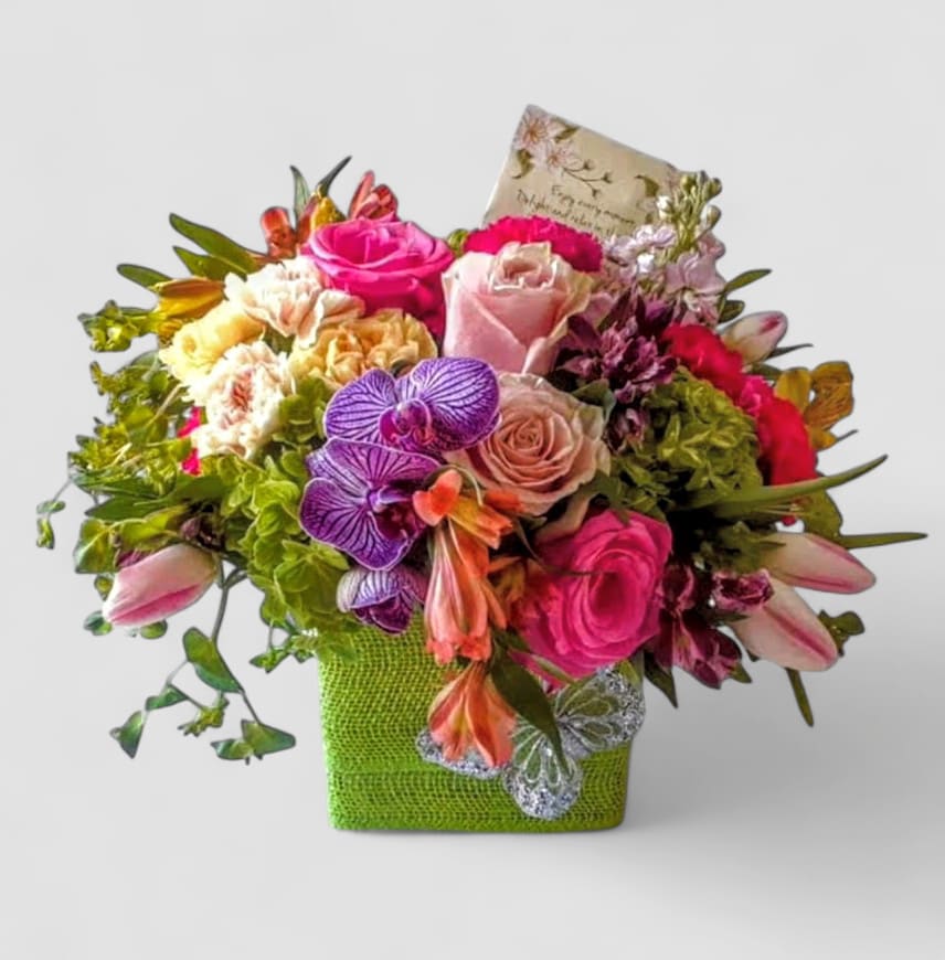 Cheerful Bouquet Designer's Choice - Roses orchids and more arranged in a modern glass cube style vase wrapped in citrus jute ribbon. Pretty and perfect to send today to show them how much you care. All of my bouquets are always made extra special and unique each and every time. Send happiness.