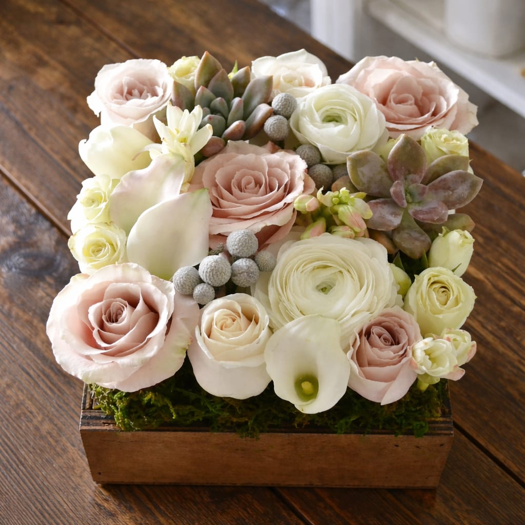 Bella  - Beautifully designed arrangement in a 7"X 7" square wood box with ivory and blush seasonal flowers, succulents are also added for the recipient's enjoyment.  Perfect for a desk or side table.  Deluxe box 8"X 8" Premium box 10"X10"