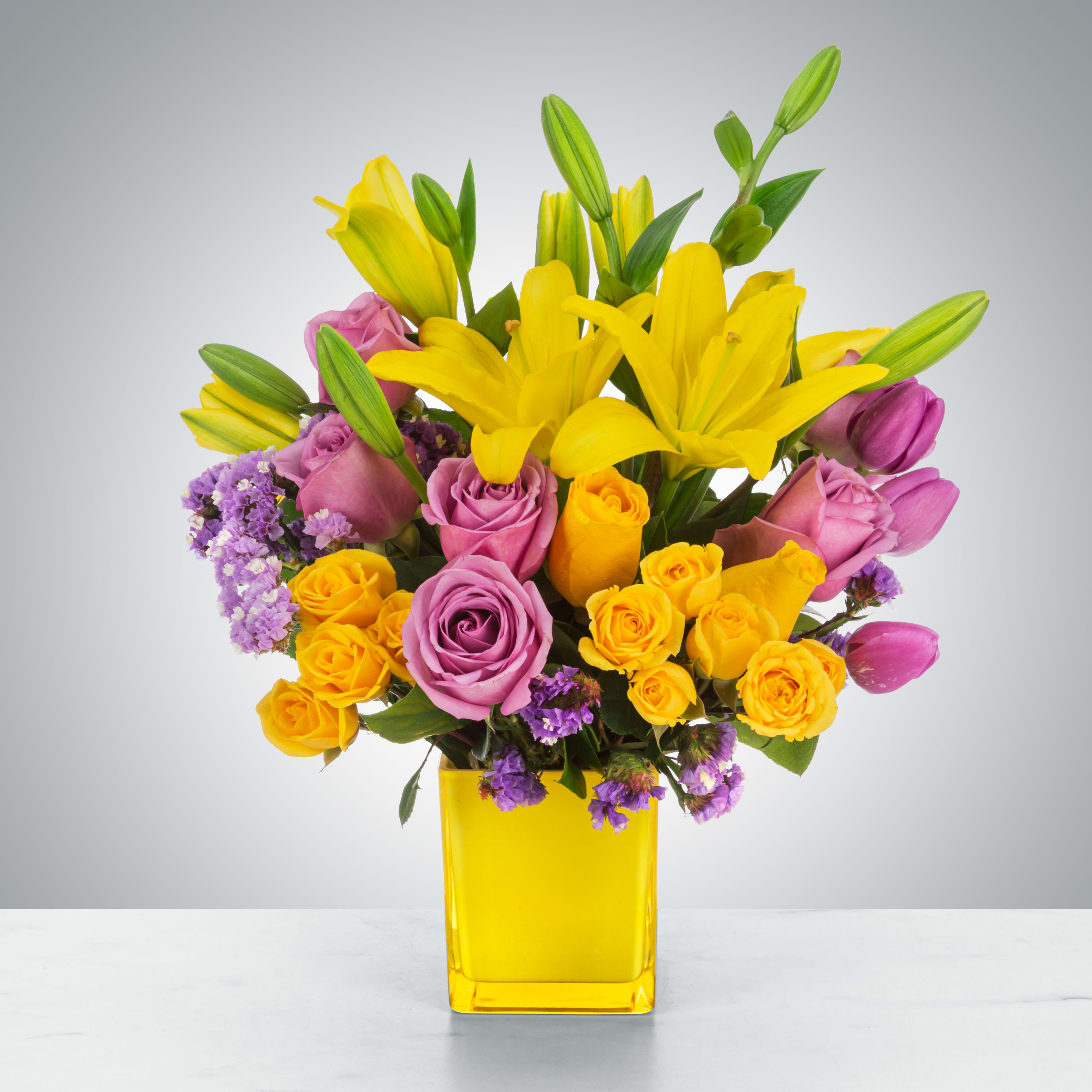 Sunday Afternoon - This arrangement is a sweet surprise for any recipient. Featuring a selection of yellow and purple flowers in a yellow vase, this arrangement is springtime in flower form and a great gift for Easter or Passover.  Approximate Dimensions: 13"D x 16"H