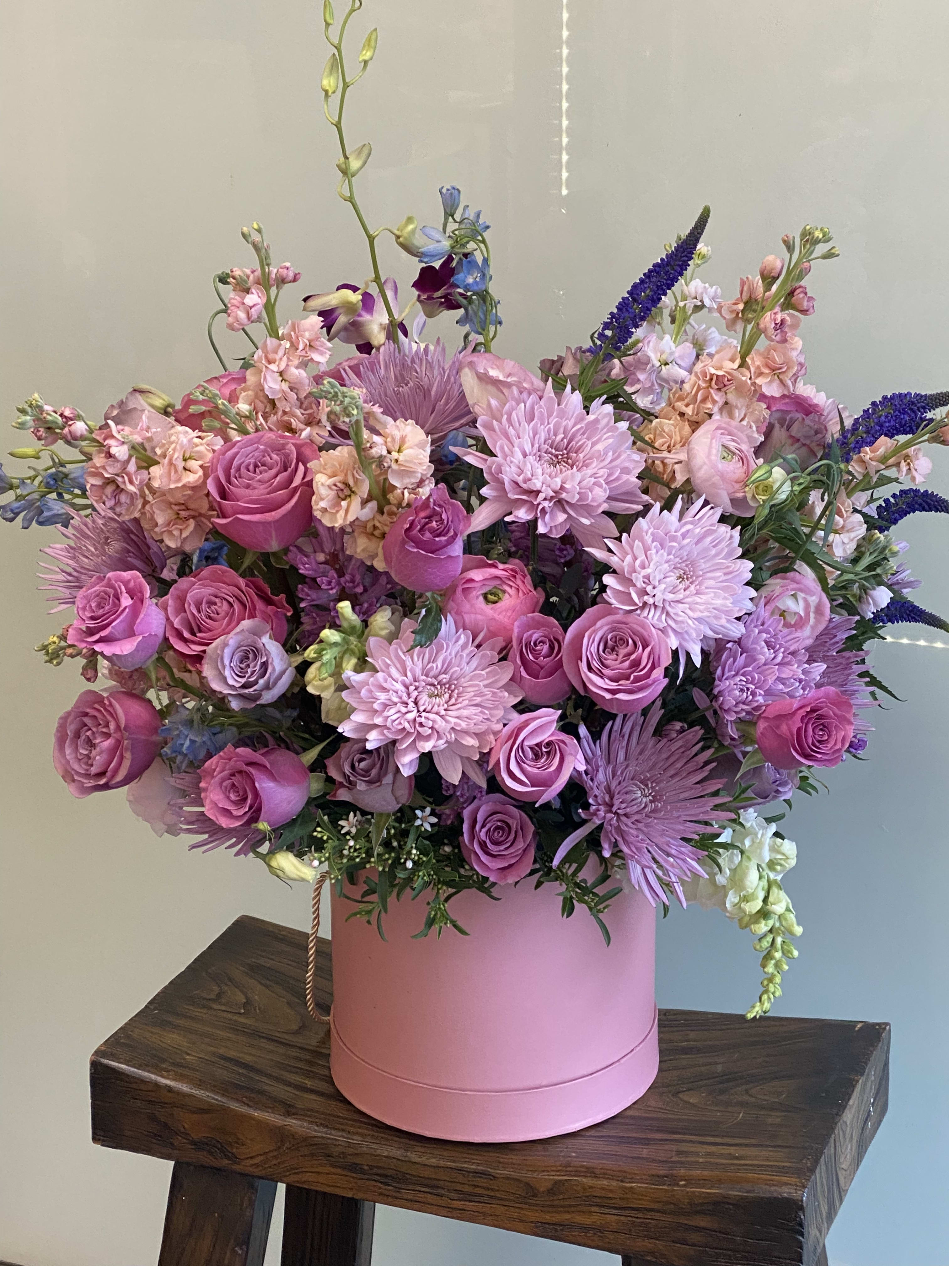 Alina's Garden of Whispered Dreams  - A romantic garden-inspired arrangement blooming with shades of blush ,Levander ,and soft pink. Delicate roses airy seasonal florals, and textural blooms are truly composed in a soft pink hat box ,evoking a dreamlike walk through an enchanted Alina's garden. Elegant ,feminine ,and endless romantic -designed to feel like a love story in bloom.  premium/deluxe upgrade elevate your arrangement with an increased fullness ,and refine luxury flowers .