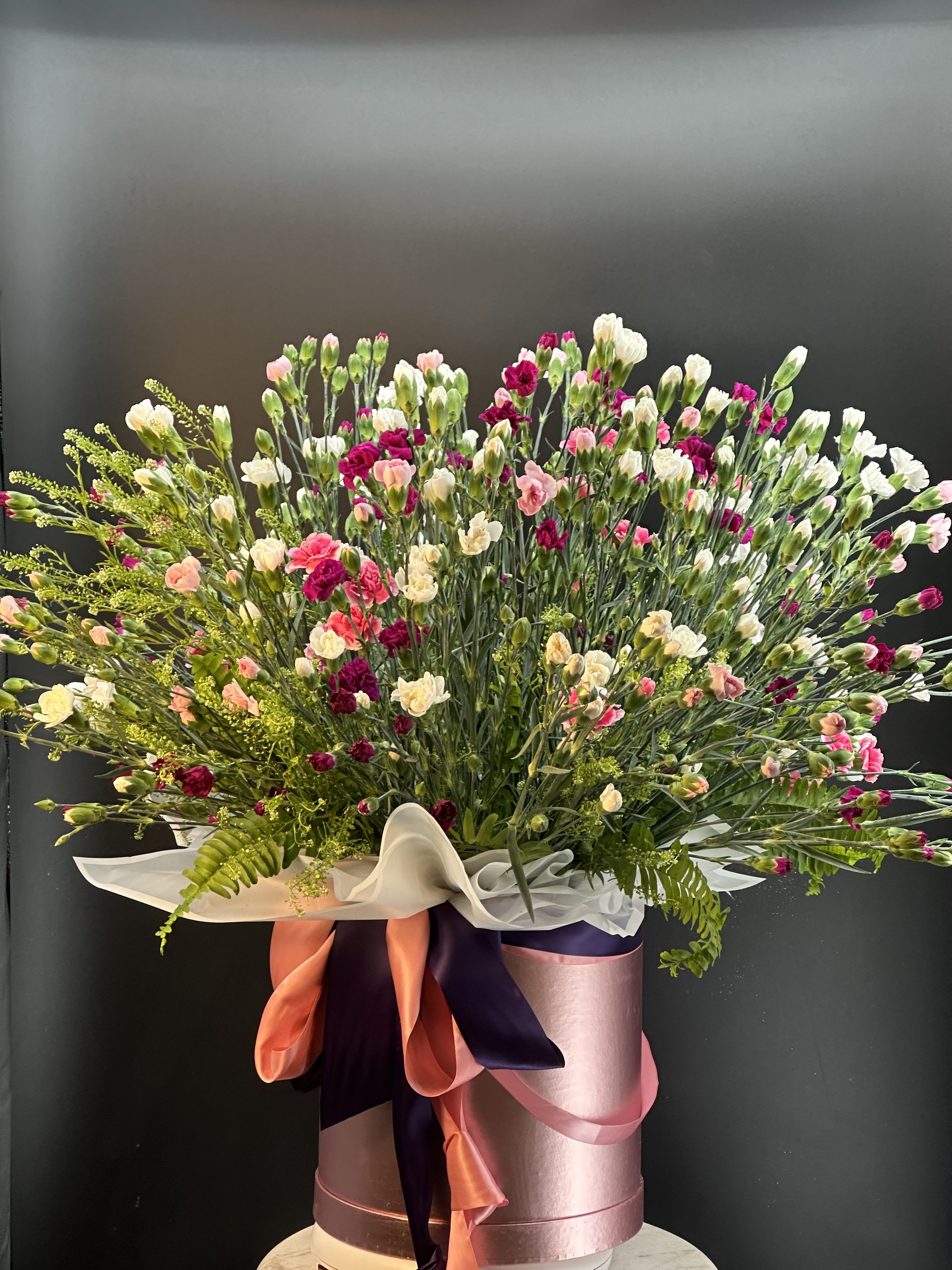 Cranston 100 - This arrangement is a full , mix carnation ,with greenery  ,garden -style celebrating bouquet that feels joyful ,abundant, and softy elegant .It wide and lush with a gently silhouette, designed to feel overwhelming and generous rather that structured.The composition spreads outward naturally ,creating a sense of movement and life . Amazing gift for someone who's love carnations. 