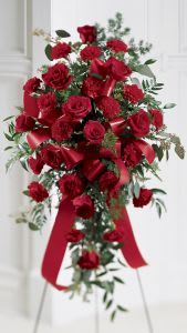 Roses &amp; Carnations Standing Spray - Red Carnations and red roses are elegantly arranged and accented with a ribbon in this beautiful spray. Arrangement is delivered on an easel and is appropriate to send to a funeral home or service and can be made in other colors available upon request.