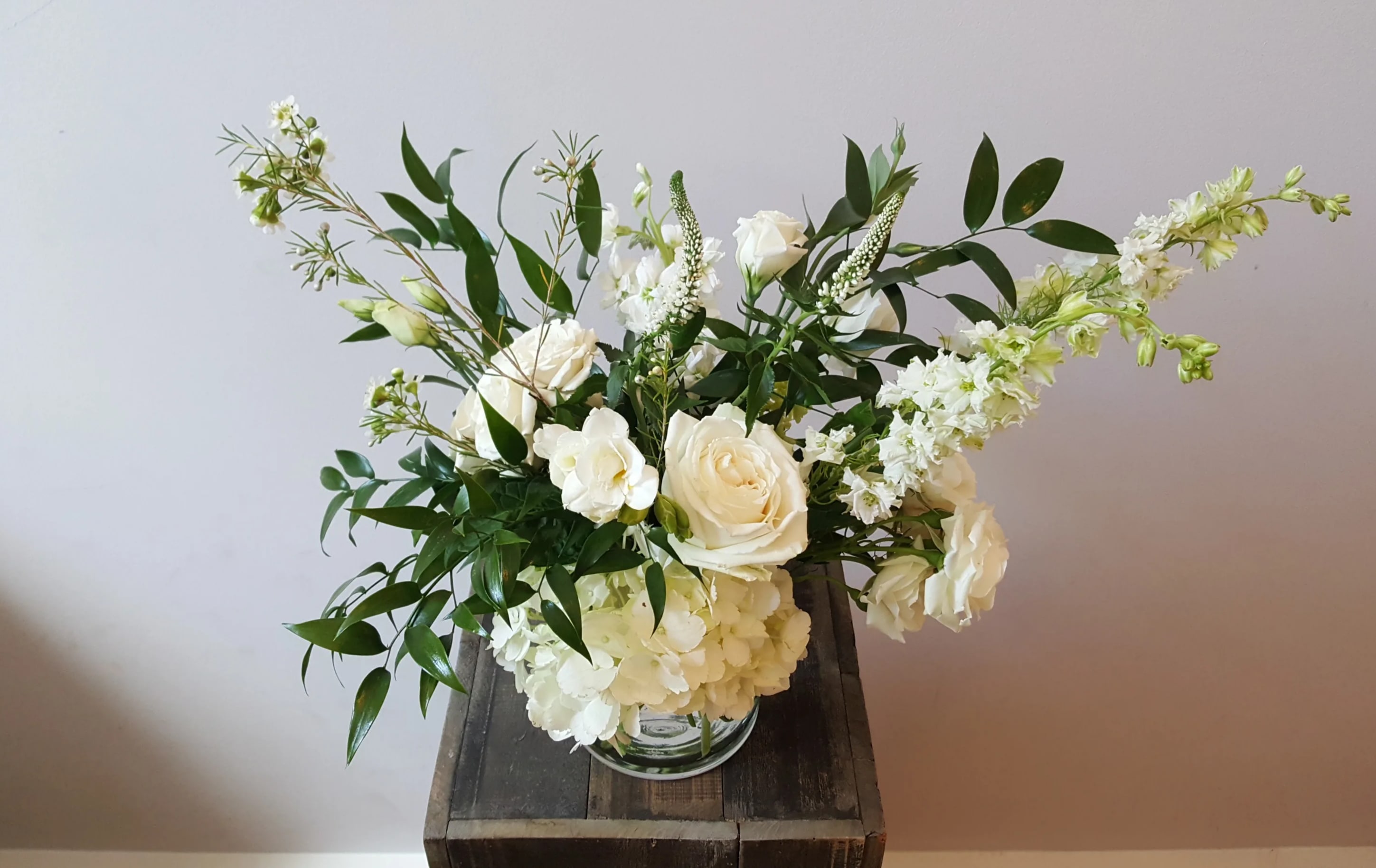 Wild Elegance - Elegant, soft, and full arrangement featuring larkspur, freesia, lisianthus, and other seasonal lovelies in shades of whites and greens.  Standard arrangement is in a 5x5"clear glass cylinder vase.