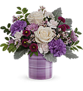 Serene Swirl Bouquet - Swirling with hand-painted bands of soft lavender, this sweet ceramic keepsake vase makes a marvelous Mother's Day gift filled with a bouquet of creamy roses and purple blooms. Light pink roses, white asiatic lilies, pink carnations, lavender stock and lavender cushion spray chrysanthemums are arranged with lavender sinuata statice, silver dollar eucalyptus and huckleberry. This Mother's Day arrangement is delivered in Teleflora's Lavender Whimsy vase.. Approximately 15 1/2" W x 20 3/4" H