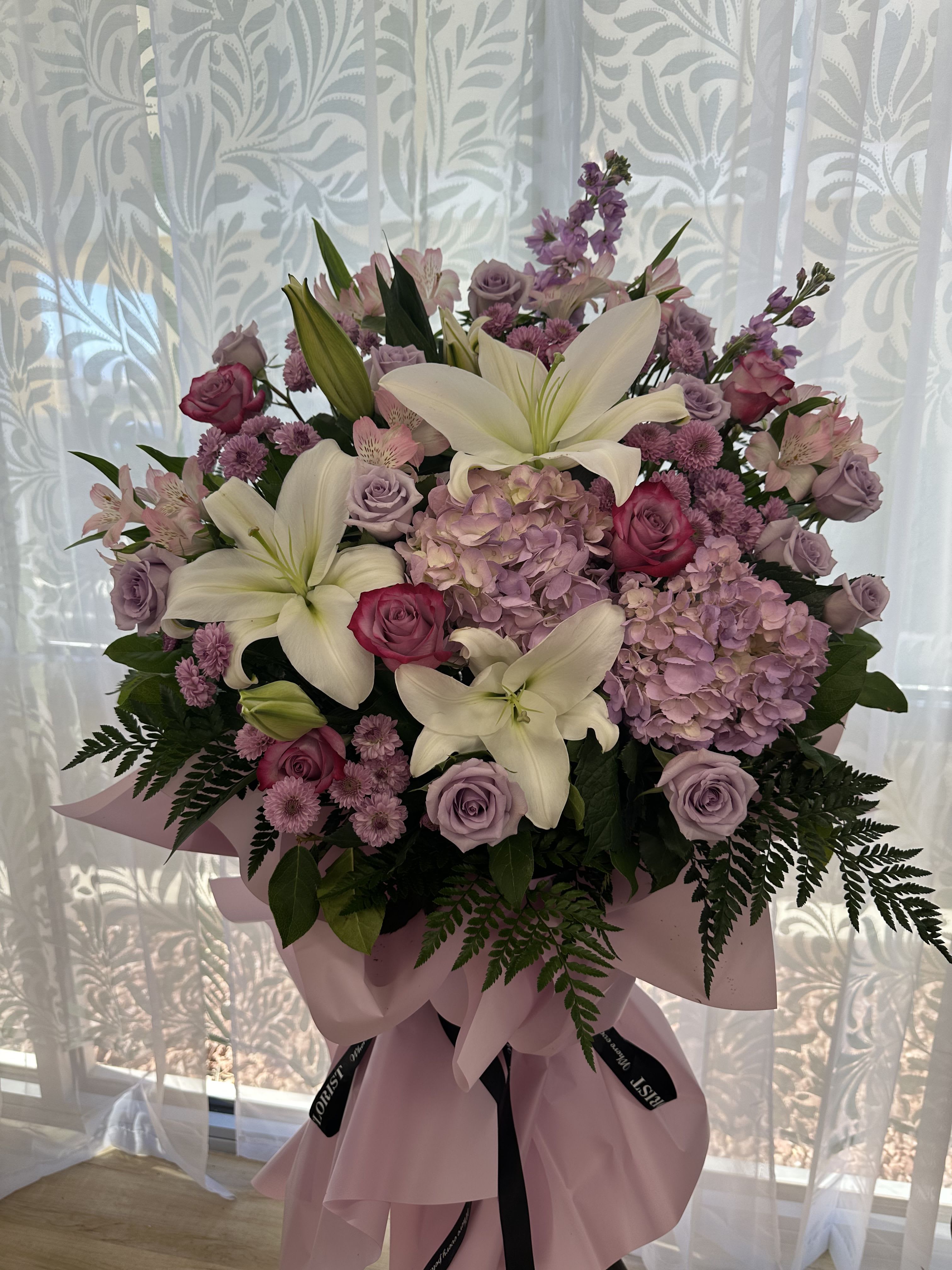 Grand opening basket lavender theme - The future has never shone brighter than now. Send your best wishes to a new business grand opening with this flower arrangement. The arrangement features roses in lavender colors, white lilies, lavender carnations, and lavender hydrangeas.
