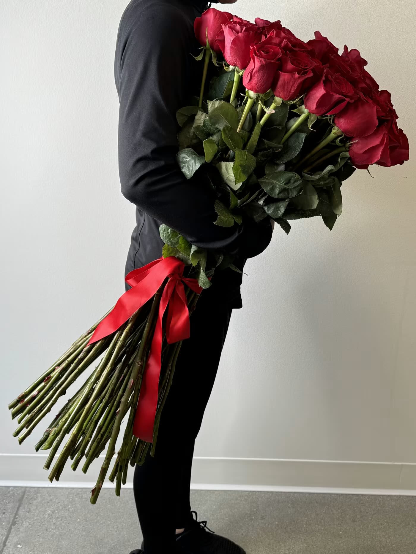 Red Roses- 3ft - Prepare for a love story of unforgettable scale with Flower Synergy’s show-stopping signature arrangement—2 dozen ultra-long-stem red roses, artfully designed as a bold and timeless declaration of love. Available by special order with at least one week’s notice, these striking roses stand nearly three feet tall, expertly bundled and finished with a classic red satin ribbon.  Designed in a tall, clear cylinder vase, this arrangement is nothing short of dramatic—lush, sculptural, and overflowing with passion. Each velvety crimson rose symbolizes deep devotion and enduring romance, their impressive height and fullness creating a breathtaking visual impact from every angle.  This is more than flowers—it’s a statement. A grand expression of love, crafted with intention and delivered with care by the designers at Flower Synergy. Perfect for life’s most meaningful moments, this towering arrangement arrives fresh, flawless, and ready to leave a lasting impression. Order in advance online or in-store and let us create an unforgettable experience in red.