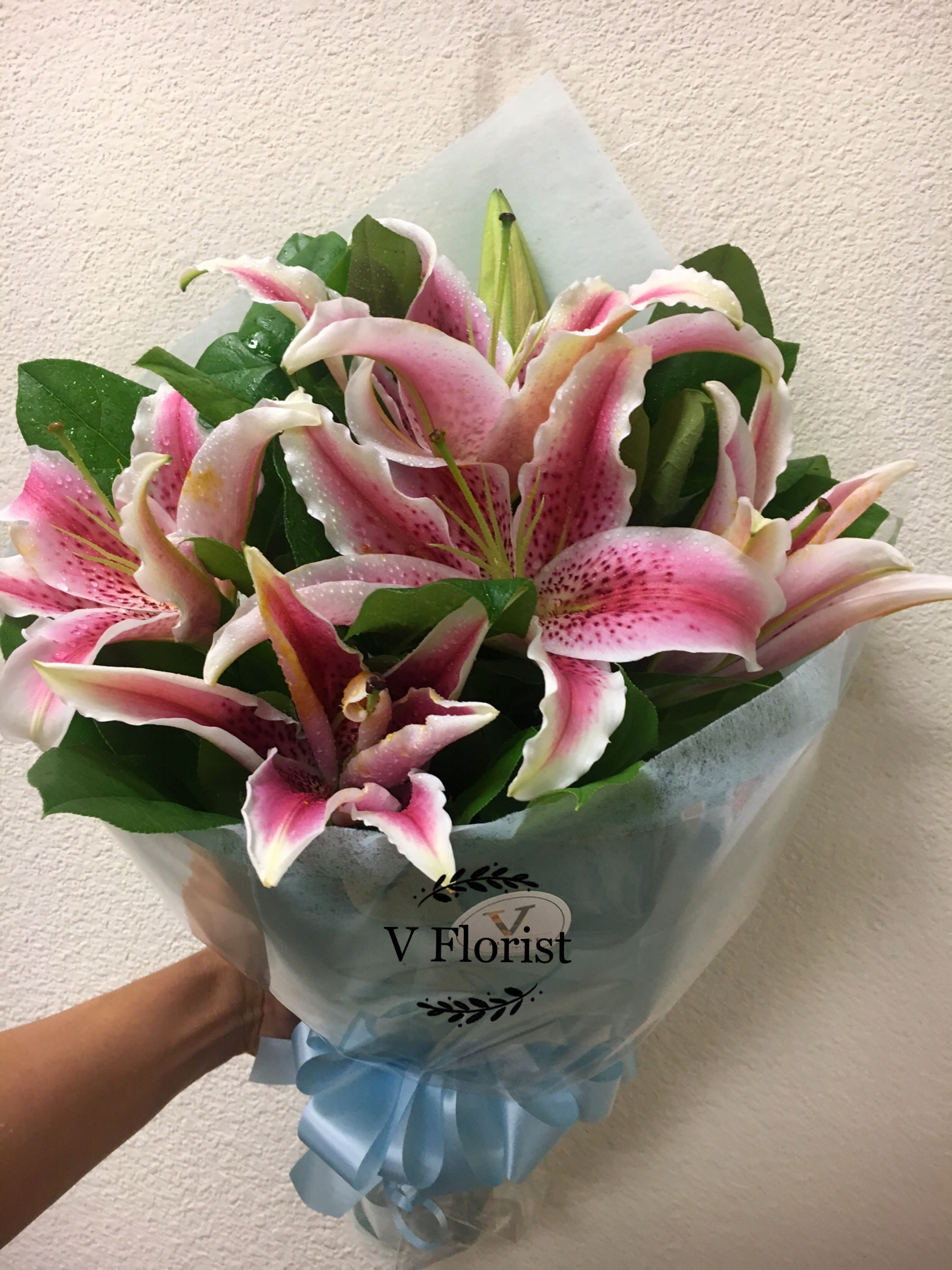Lilies Simple Wrapped Bouquet - lilies wrapped in a hand-hold bouquet with greens. Best for surprises, date night, and celebrations.  Our florists select the freshest flowers available, so colors and varieties may vary due to local availability.