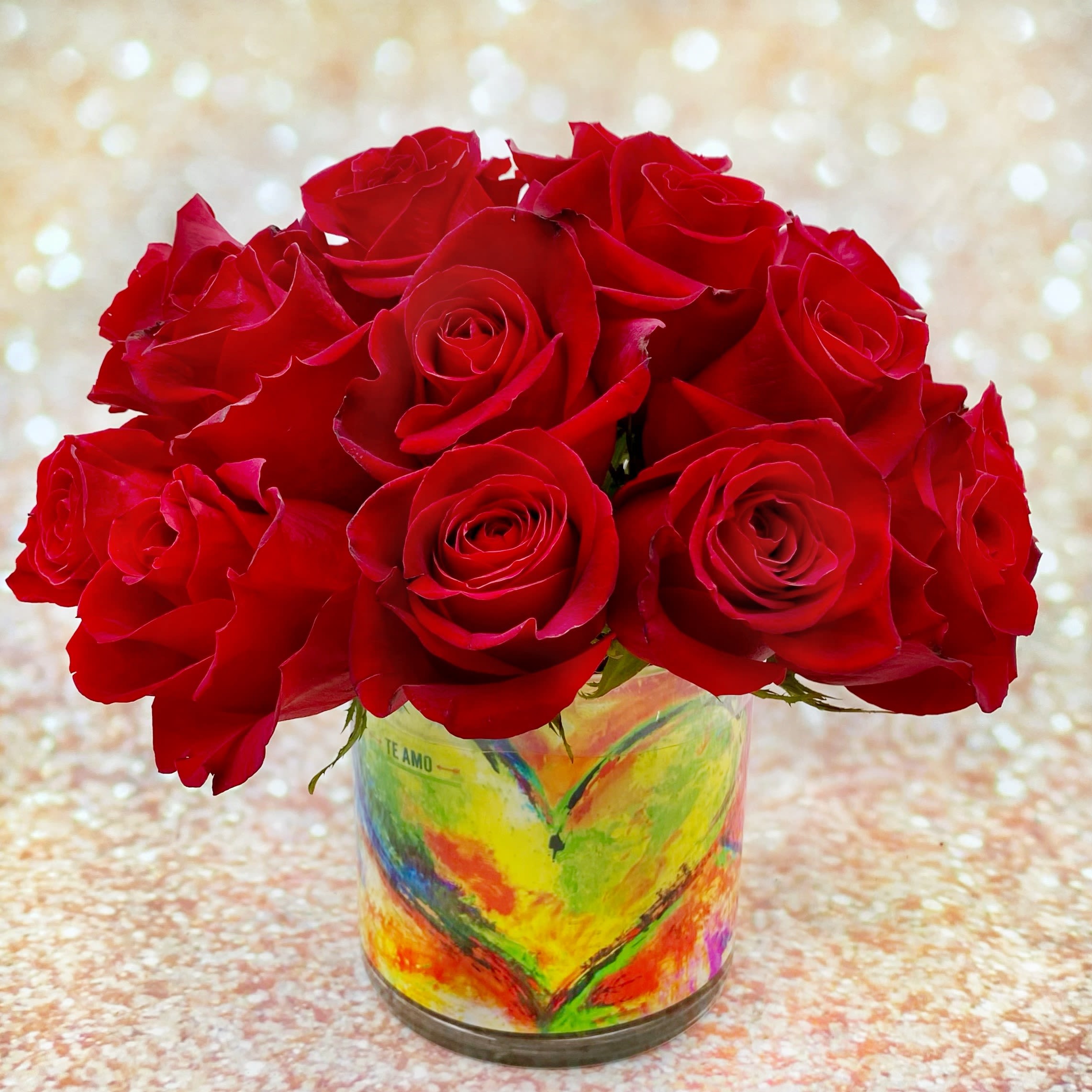 Te Amo - Two Dozen Red Roses - Te Amo means "I love you" in Spanish, making this arrangement the perfect way to communicate your feelings this Valentine's Day. One dozen perfect red roses in a classic cylinder vase. The vase is lined with a stylized double heart graphic with the words "Te Amo" subtly appearing. The graphic is printed on water-resistant paper. If you prefer hot pink roses, let us know in ‘Special Instructions’ during checkout or call us to place your order.   Standard is two dozen red roses. Choose Premium to upgrade to three dozen red roses.  Approximate Dimensions - Two Dozen: 10 inches wide by 10 inches tall Three Dozen: 11 inches wide by 10 inches tall  Orders for this Fiori Floral Design original or an address outside of our standard delivery area will have a leaf wrap inside of the vase instead of our proprietary graphic. To check if a recipient’s address is in our delivery area, see the list of Neighborhoods, Cities and Zip Codes at the bottom of our home page or give us a call at (206) 329-3944.