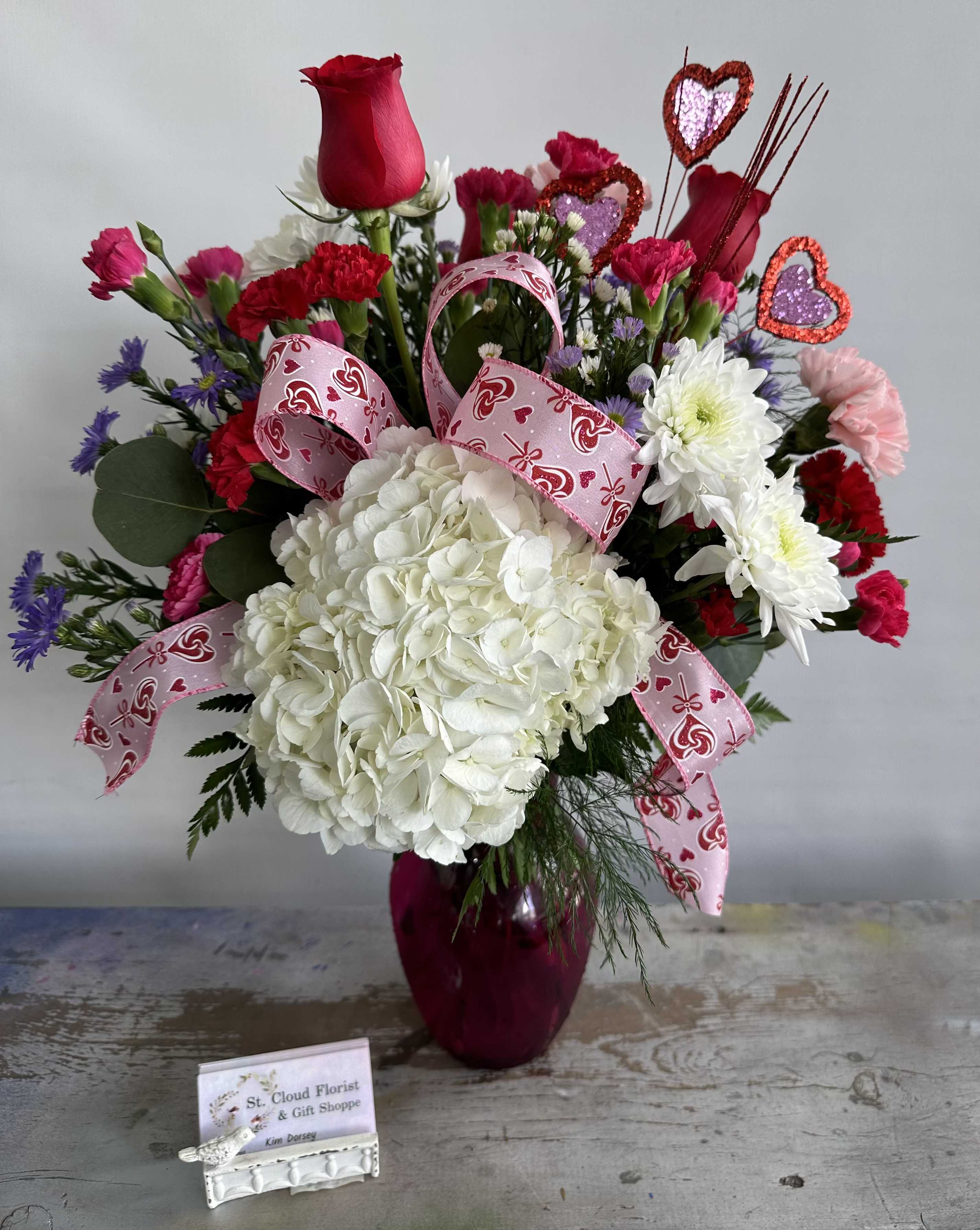 Be Mine - A gorgeous mix of roses, hydrangeas, carnations &amp; assorted vibrant flowers in Valentine's Day colors. Arrangement comes in Ombre vase. See image. While supplies last. Flowers and containers are subject to substitution.