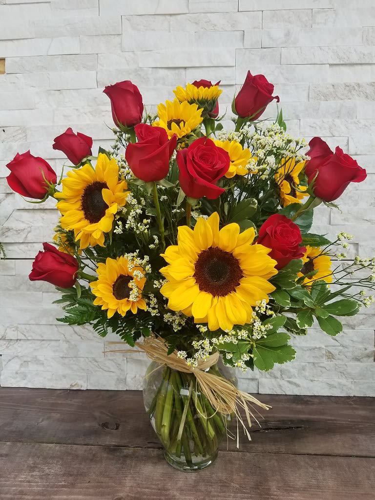 Roses and Sunflowers  - One dozen Roses and one dozen Sunflowers arranged in a clear glass vase. Tide off with a raffia bow.