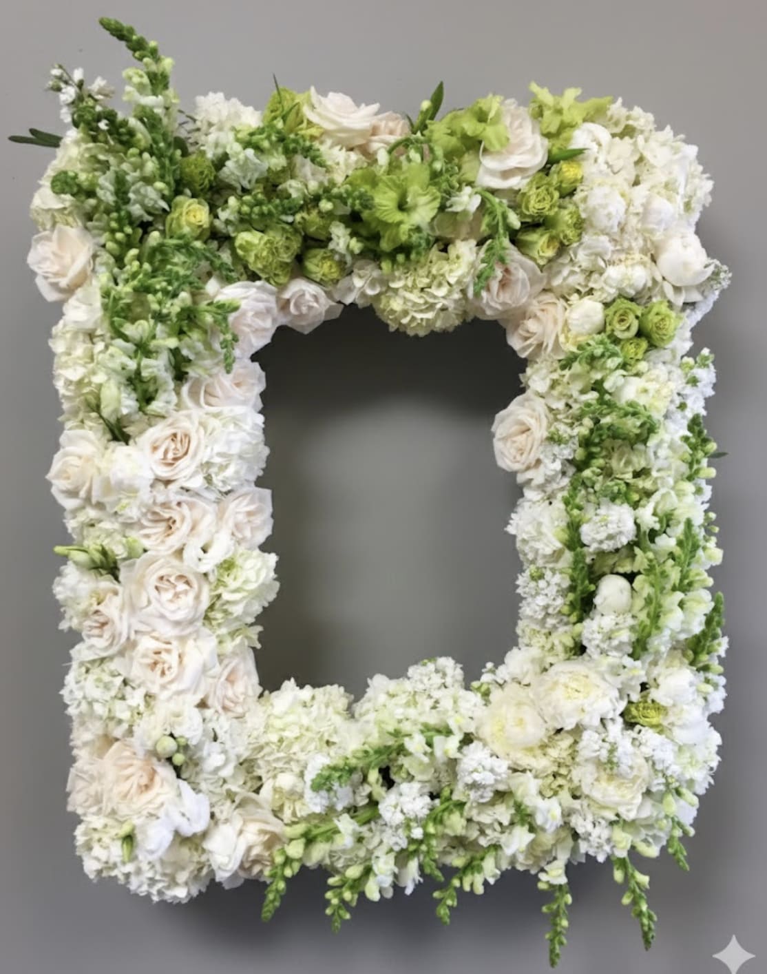 White and Green Rose Frame  - This frame includes white and green roses as well as matching snapdragons.     Dimensions of standard size frame are approximately 32x24  Large frame approximately 36x28. Frame is not included.    We include easel, printed banner, and delivery (some fees may apply). An additional banner can be added for $15.  
