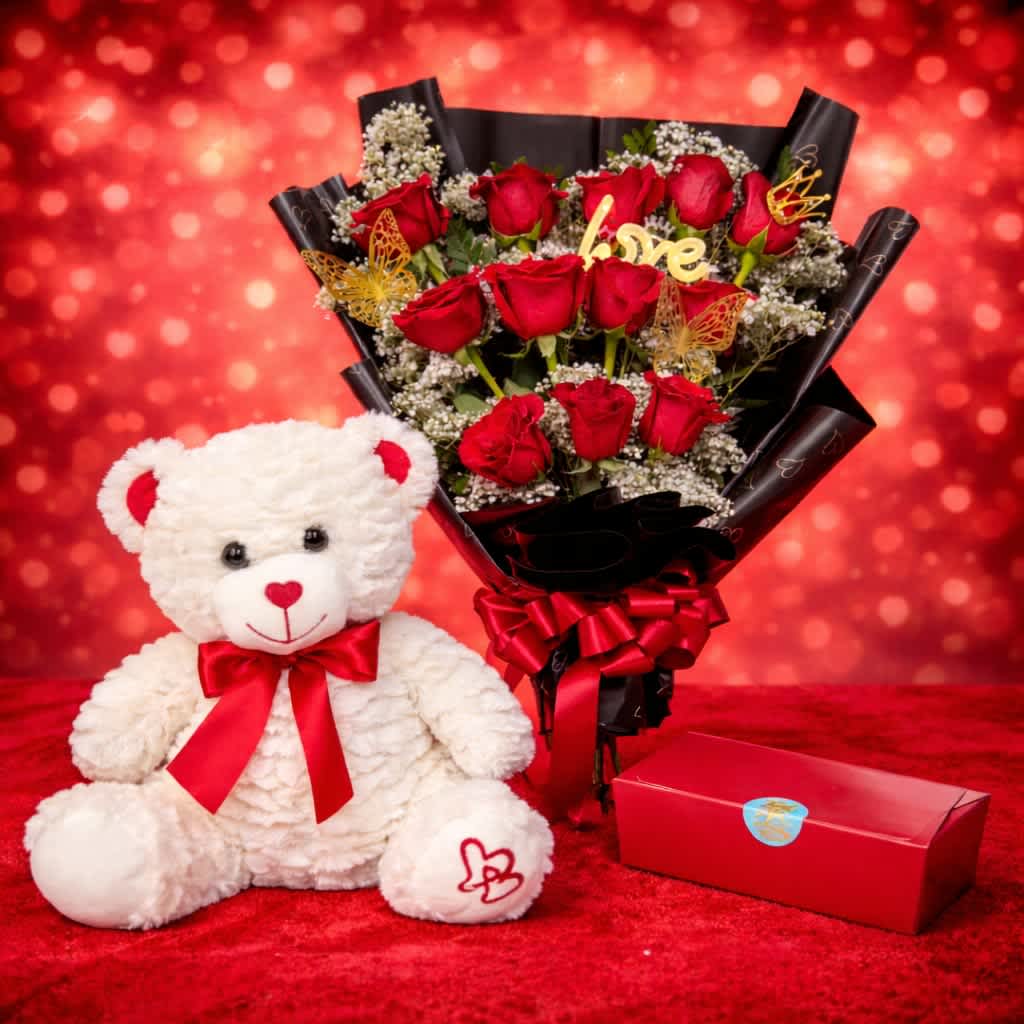 Love in Bloom Bundle - Sweep them off their feet with our Love in Bloom Bundle, a timeless Valentine’s Day favorite designed to say everything without saying a word. This romantic set features a lush bouquet of 12 premium red roses accented with delicate baby’s breath, elegantly wrapped in sleek black paper and finished with a rich red satin bow.  Paired with an irresistibly 12" soft heart print teddy bear and a classic dozen chocolate gift box, this bundle is the perfect expression of love, warmth, and affection. Whether you’re celebrating a new romance or a lifelong love, Love in Bloom delivers a heartfelt moment they’ll never forget.   Want to make it even more special? You can enhance this gift by adding a Valentine’s Day balloon, available in our Valentine’s Day section, for an extra festive and romantic touch.