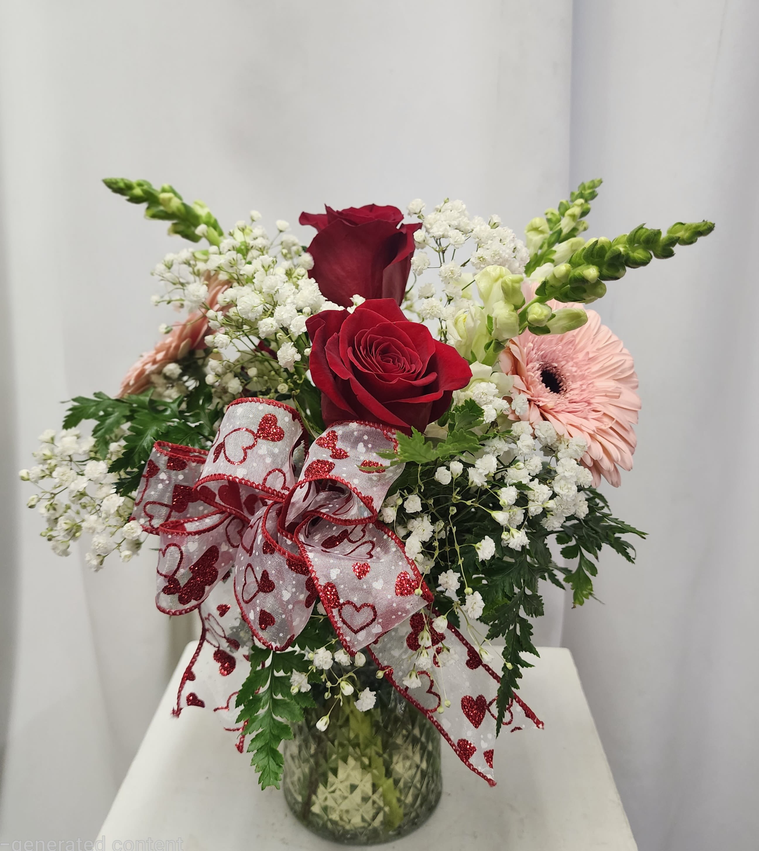 Valentine Kisses - Red Roses, pink gerbera daisies, white snapdragons and babies breath with an eye catching bow of hearts.  This arrangement says love and cherished with soft and elegant appeal. 