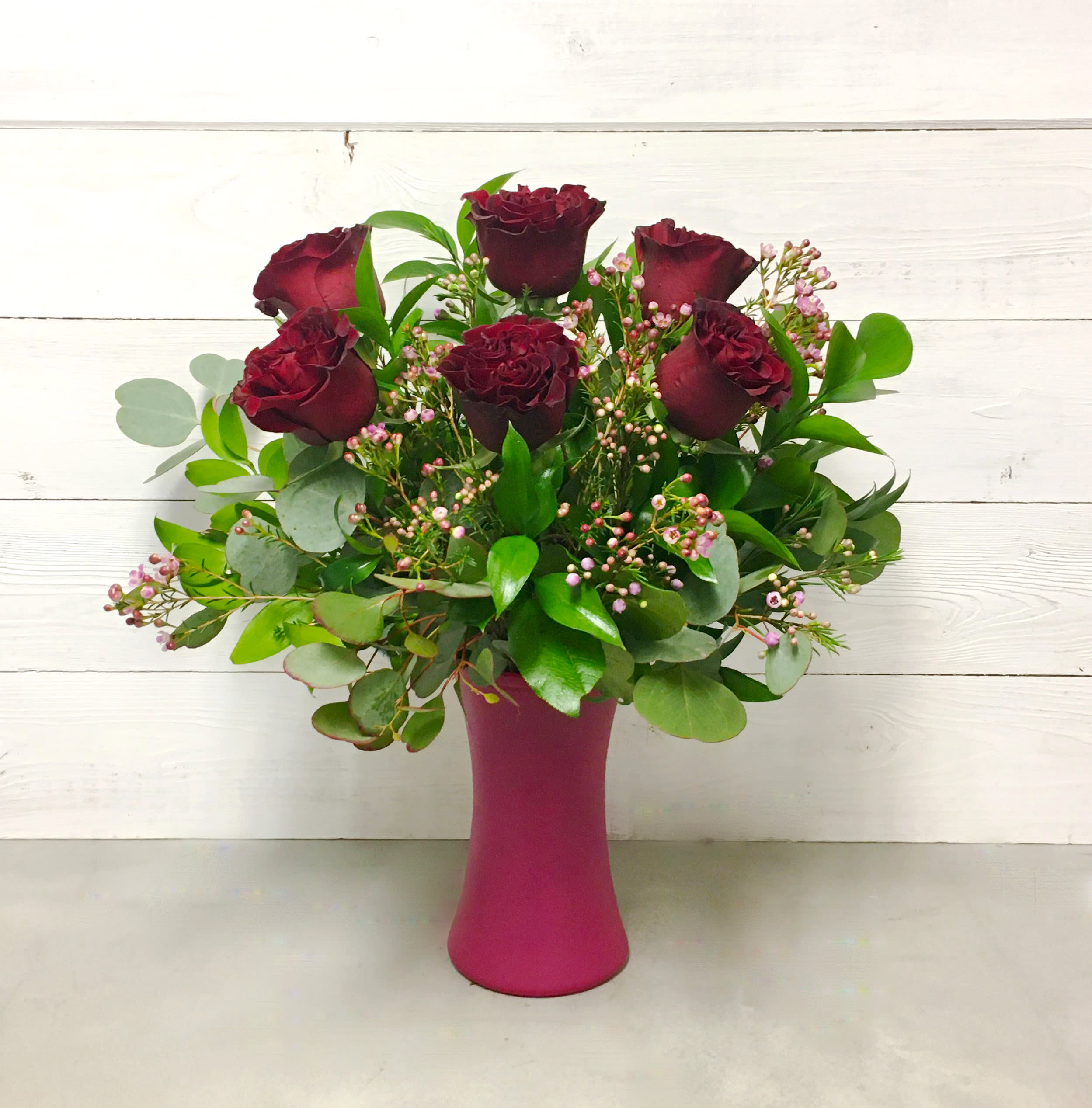 Rosa - This arrangement features 6 of our premium long-stemmed red roses accented with greens and filler designed in a clear glass vase. 