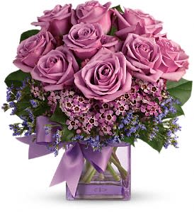 Morning Song - Shades of purple are in perfect harmony in this profoundly pretty arrangement. A lovely mix of classic and modern, ribbons and roses, it's sure to make someone's day!  Lavender roses and wax flower, purple limonium and greens are hand-delivered in a cube vase that's all wrapped up with a vibrant purple taffeta ribbon.  Approximately 10 1/2" W x 11" H  Orientation: One-Sided  As Shown : DG68-3AB