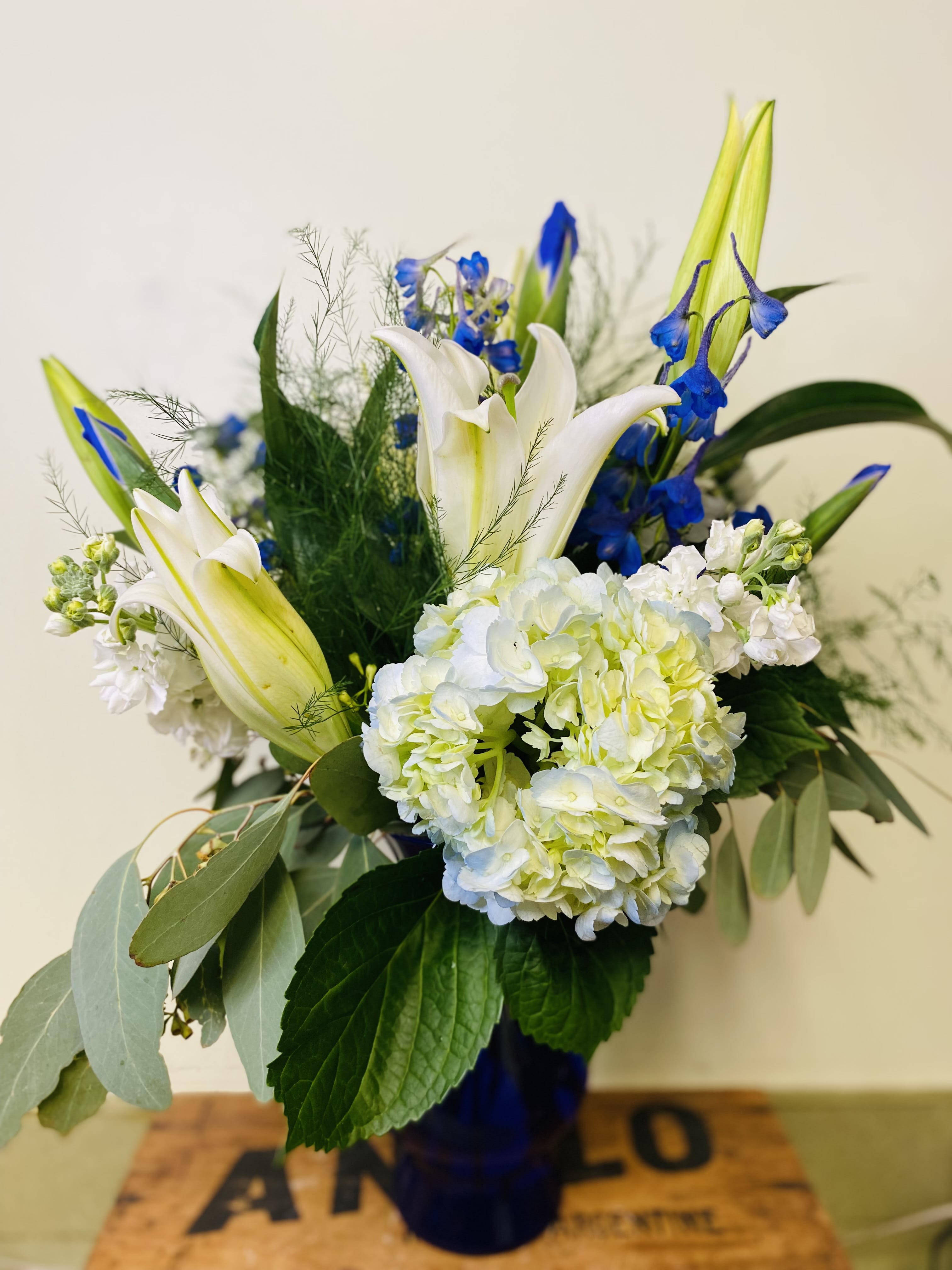 Moody Blues - A fresh assortment expertly arranged in a blue vase with Delphinium, Hydrangea, Oriental lily, Iris, Stock and  lush assortment of greenery. Perfect for any occasion! 