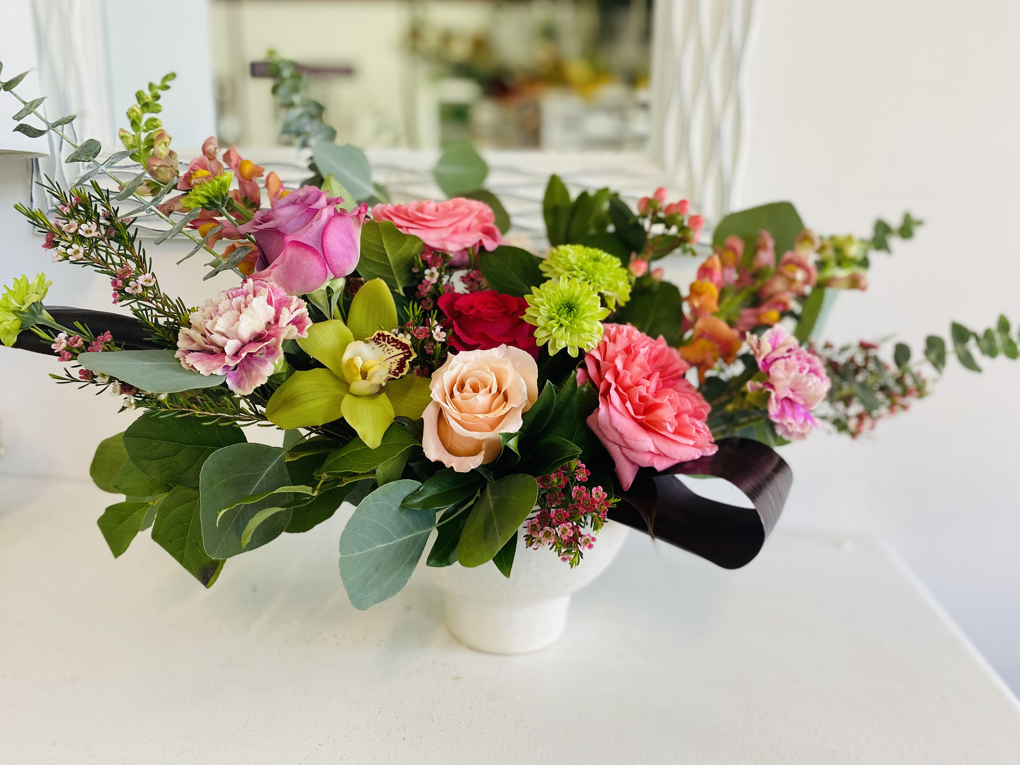 Best Blooms - A beautiful arrangement  with roses orchids and sesonal blooms and fillers arranged in a compote keepsake vase.