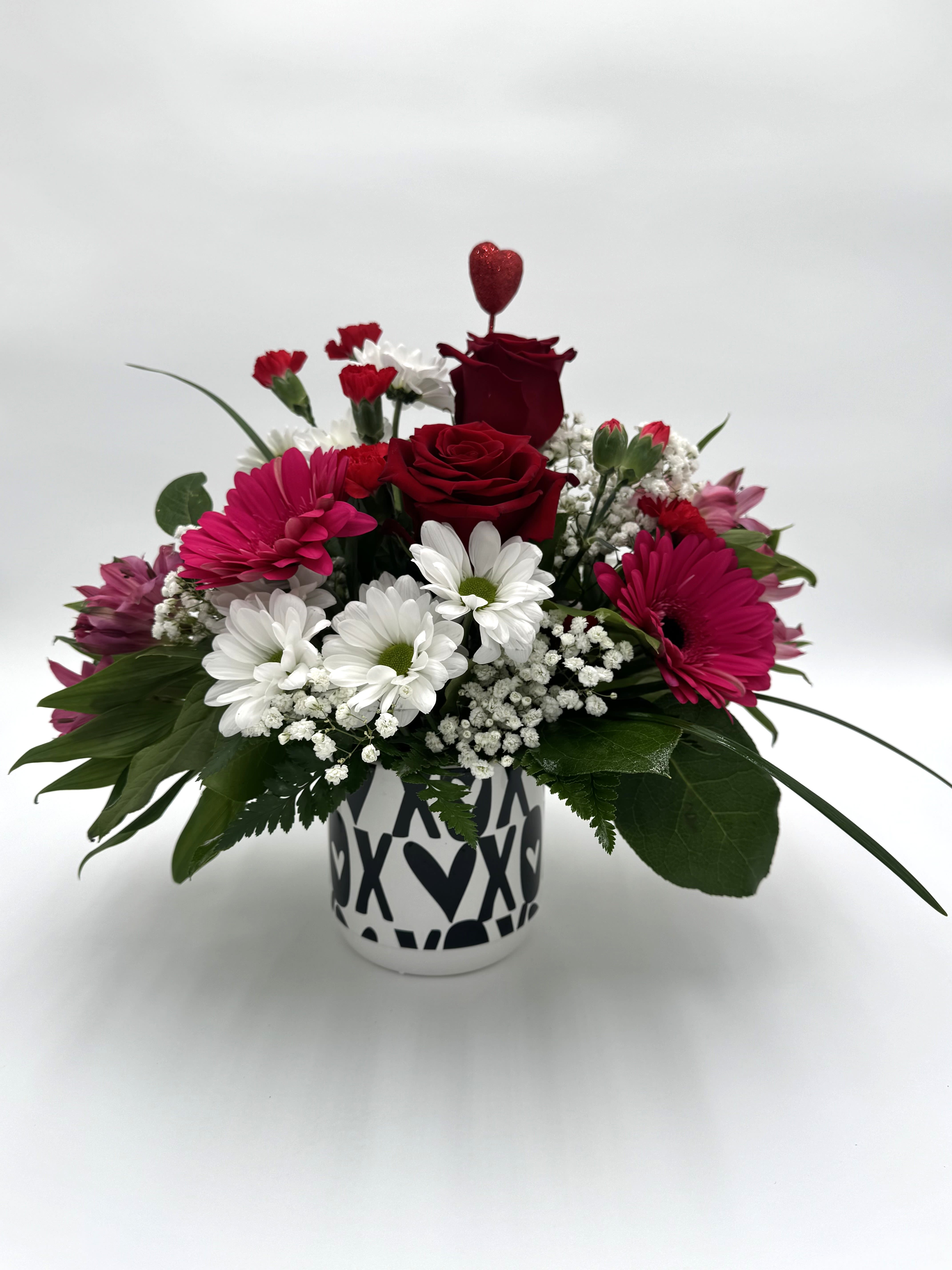 Sweetheart Blooms - A charming mix of red roses, pink gerbera daisies, and crisp white blooms, arranged in a playful heart-patterned keepsake mug. A perfect way to say “I love you.”