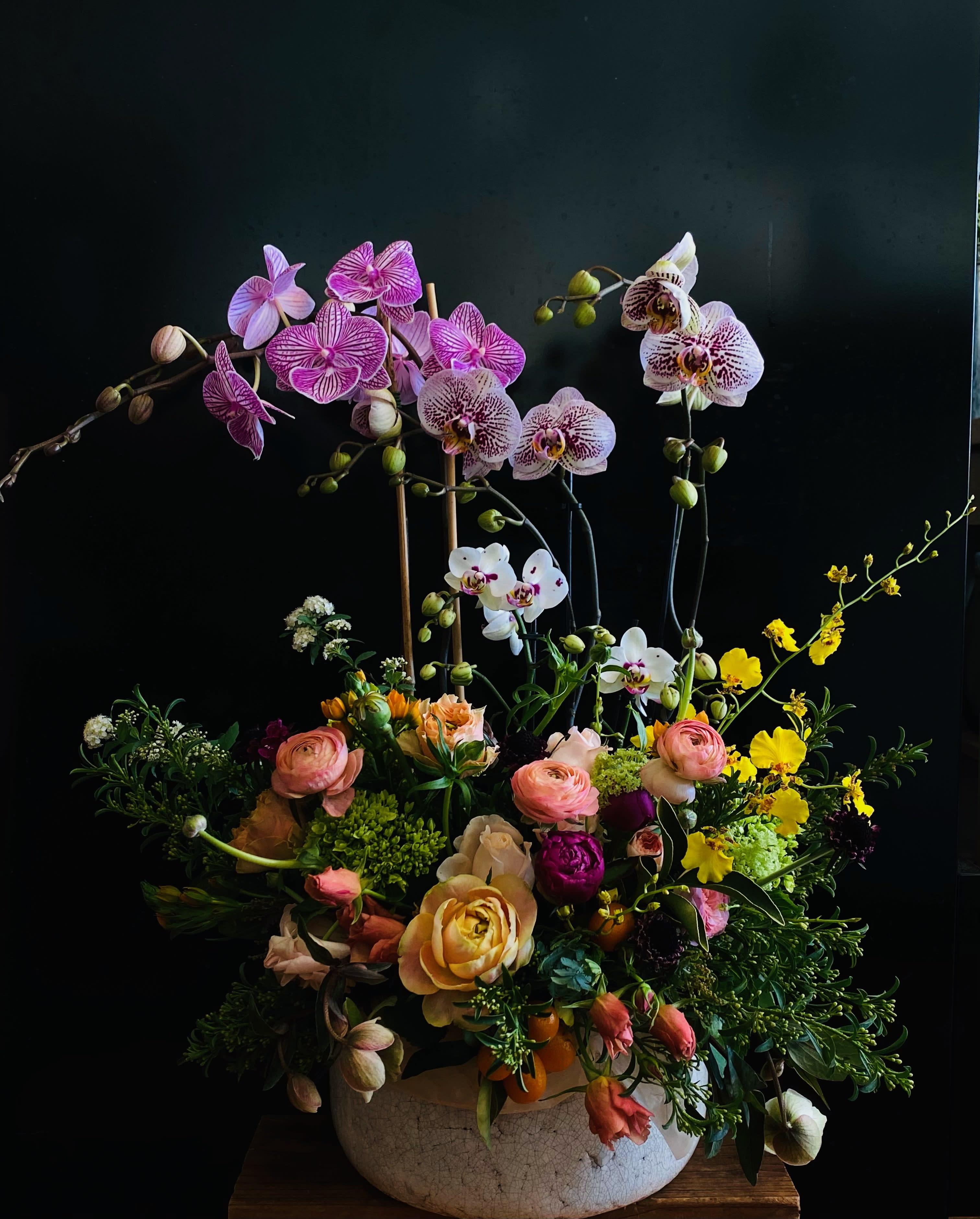 Miyabi - This one is really special. Miyabi is hard to translate. Momo sees it as "Gorgeous, yet humble." Miyabi seeks to impress. But Miyabi doesn't brag. It has a certain dignity. Even while it flaunts its beauty, it keeps its composure. Miyabi doesn't say "look at me, look at me!" It doesn't have to. You already are. Miyabi features Momo's personal selection of live orchids in a bed of live plants and a kaleidoscope of various cut flowers in a earthenware artists pot.