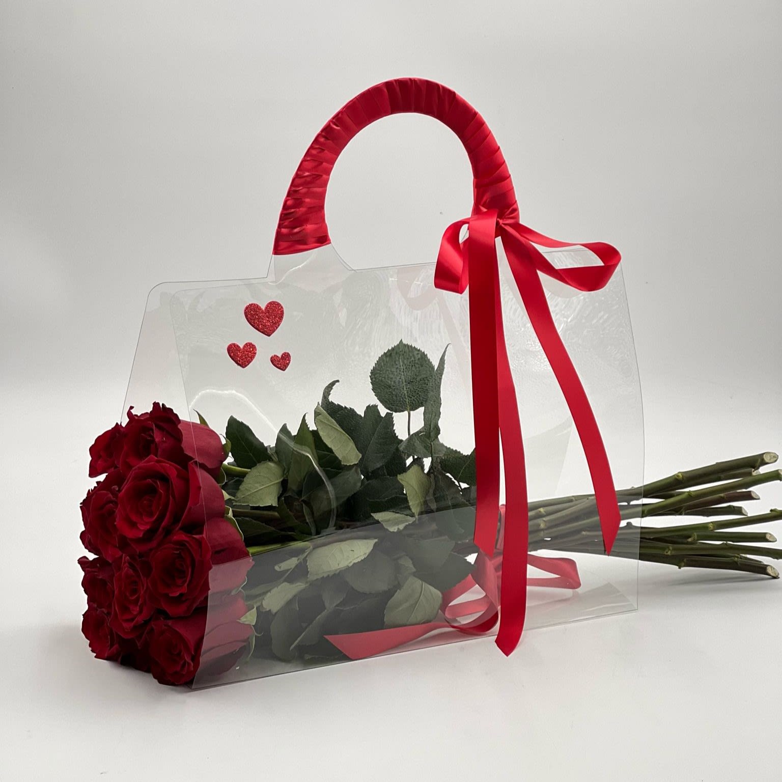 Happy Valentine's Day - An elegand bouquet of vibrant red roses designed in a clear plastic bag, tied with a red ribbon, ready to be gifted on special occations like the Valentine's Day, International Women's Day, Mother's day.