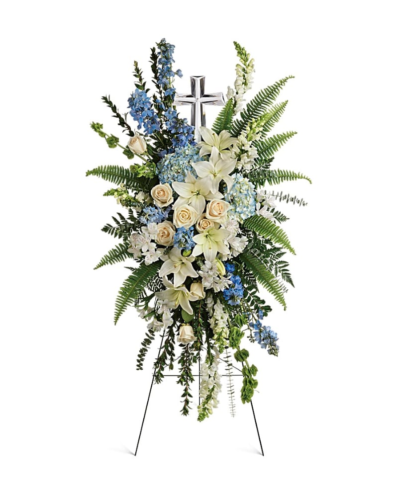 Eternal Grace Spray - Celebrate the eternal grace of a life well lived with this dramatic spray of peaceful white and blue blooms, crowned with a large crystal cross keepsake. This serene spray includes blue hydrangea,crème roses, white asiatic lilies, white alstroemeria, bells of Ireland, blue delphinium, white snapdragons, myrtle, sword fern, leatherleaf fern, spiral eucalyptus, and variegated pittorsporum. Delivered on a wire easel with a Crystal Cross Keepsake.