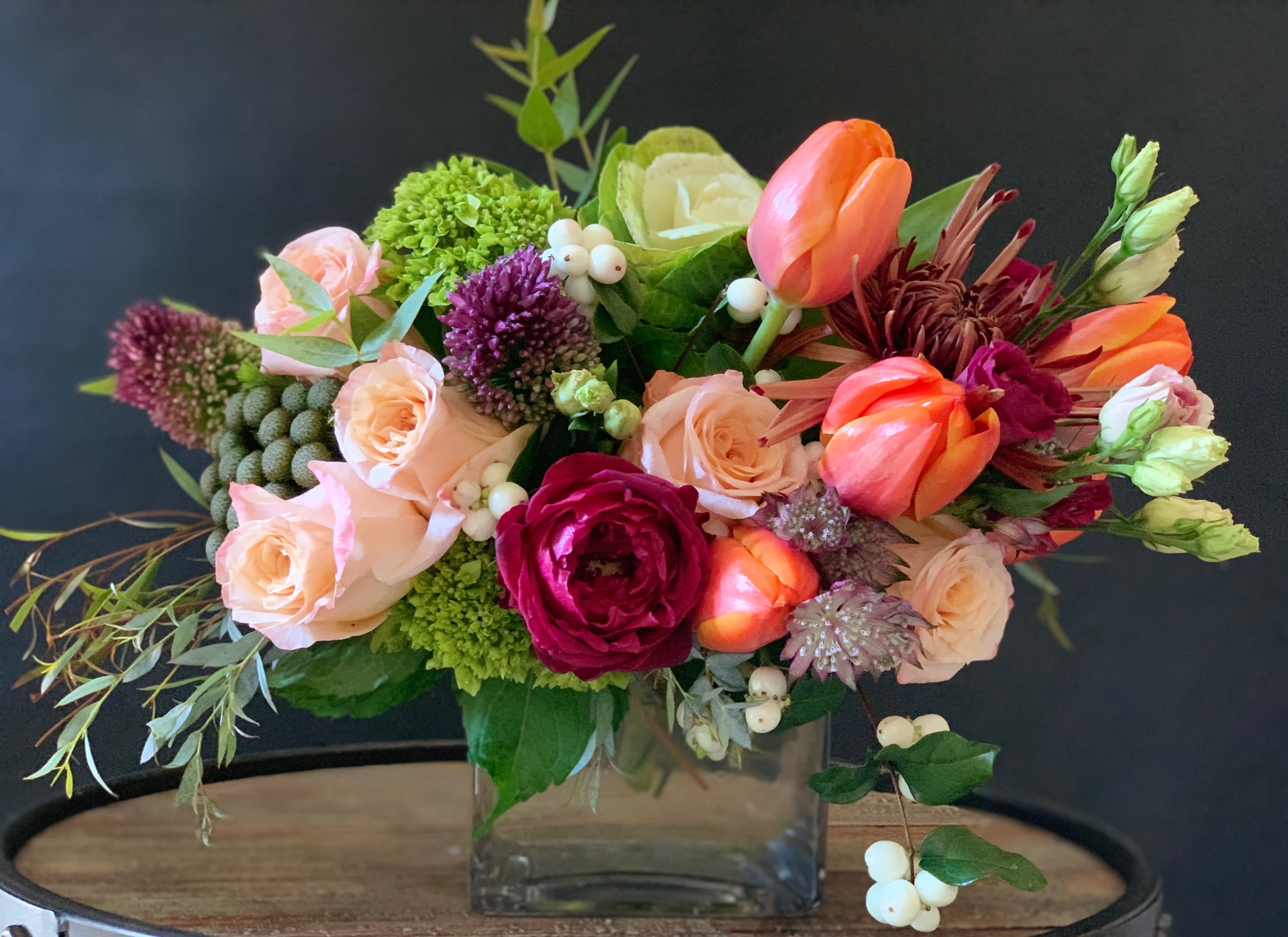 SARA - Designed with agapanthus, tulips, hellebores and roses, this vibrant and colorful arrangement sends a clear message of happy feelings to your loved ones.  
