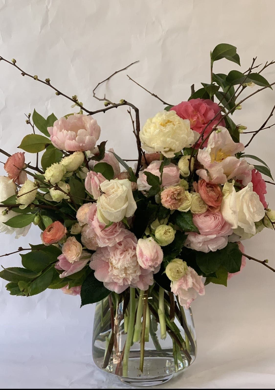 Blushing Beauties - Upright floral expression tied with branches and greenery.