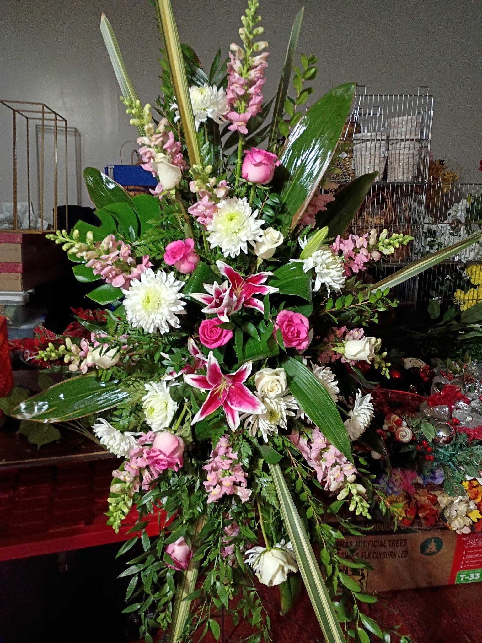 Faithfully Pink Standing Spray - Beautiful standing spray with pink stargazers, hot pink roses, pink stock, white dengarden, and a mix of tropical greenery for a beautiful look.
