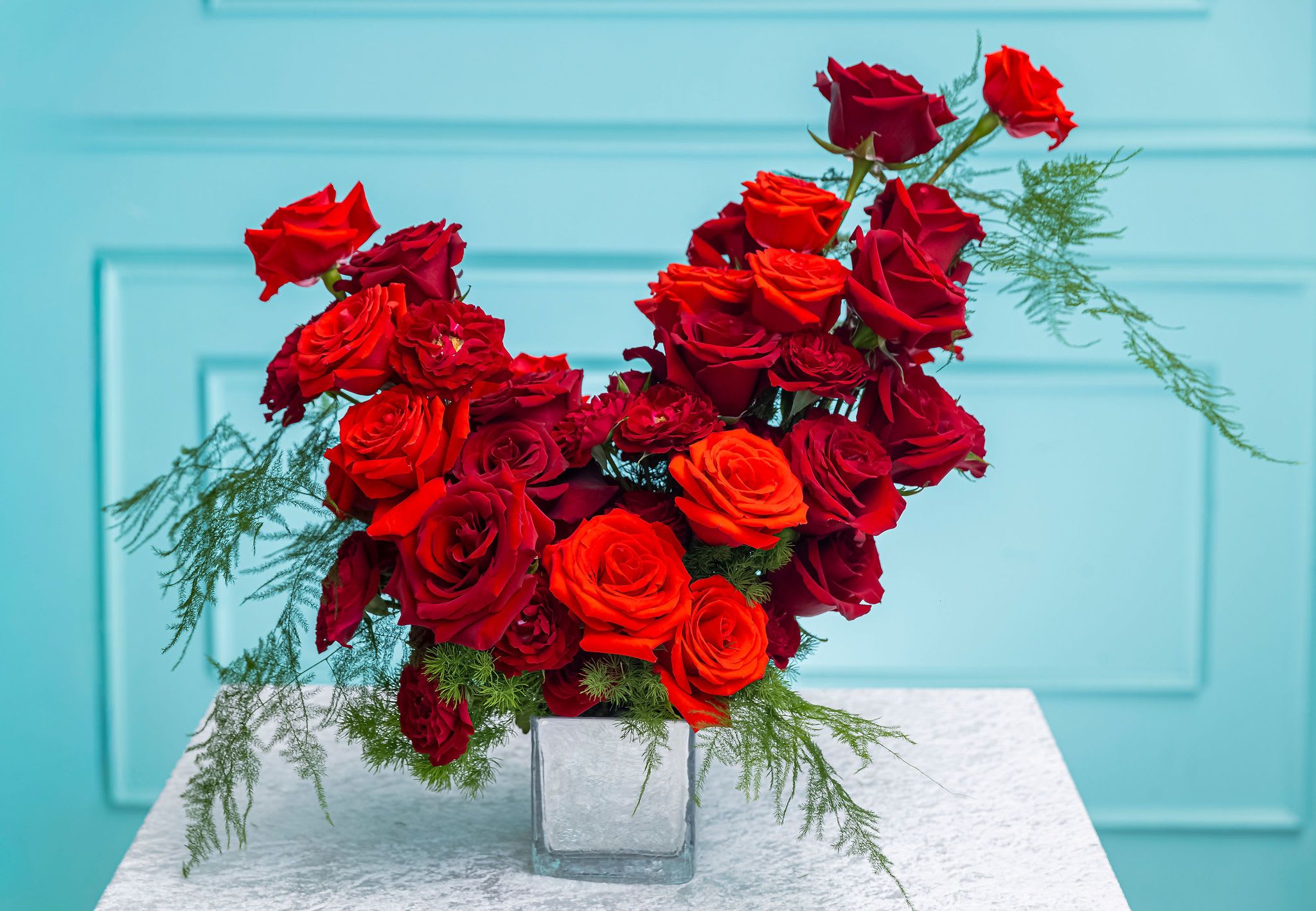 The Julia - Ignite the senses with this striking arrangement that perfectly balances romance and modern flair. Bold red roses and sleek greenery take center stage, each bloom showcasing its own unique texture and shape. Wispy eucalyptus branches add subtle movement and a refreshing hint of green, bringing harmony to the vivid red palette.  This exotic red arrangement is designed to make a statement—whether celebrating a special occasion or simply adding luxurious style to any space.    Perfect for: Romantic gestures, admiration, heartfelt surprises, and luxury gifting.  