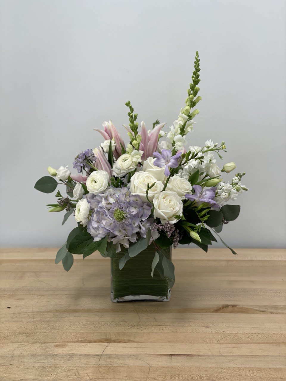Soft Breeze - This pastel color palette brings feeling of peace and calm to any setting. A combination of roses, ranunculus, hydrangea, snapdragons and premium oriental lilies. 
