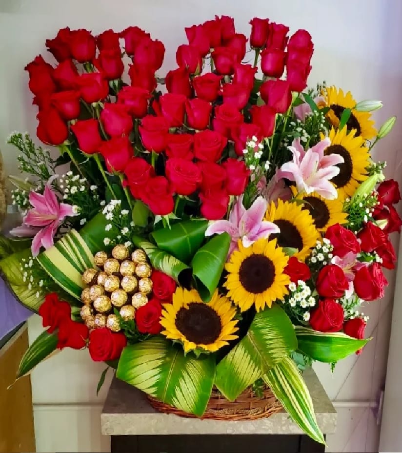 VDay 16 - This beautiful arrangement comes with 60 roses, 6 sunflowers, 4 stems of lilies and 24 chocolates and tropical greenery.                  