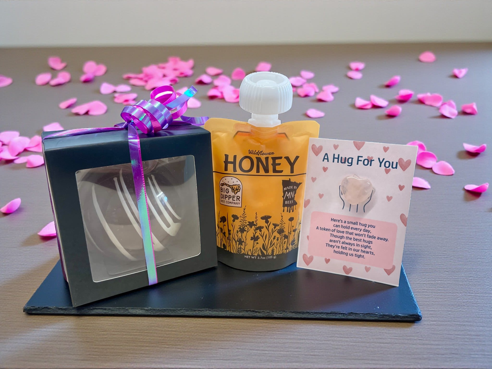 Love Bomb &amp; Honey Gift Trio - The Love Bomb &amp; Honey Gift Trio is the perfect little gesture to brighten your loved ones’ season. It features a rich hot chocolate cocoa bomb to warm those chilly days, a pouch of pure, natural Minnesota local honey for added sweetness, and a small rose quartz pocket heart to share love, positive vibes, and appreciation. Perfect for yourself or someone special, it’s all about comfort, sweetness, and a little extra love.