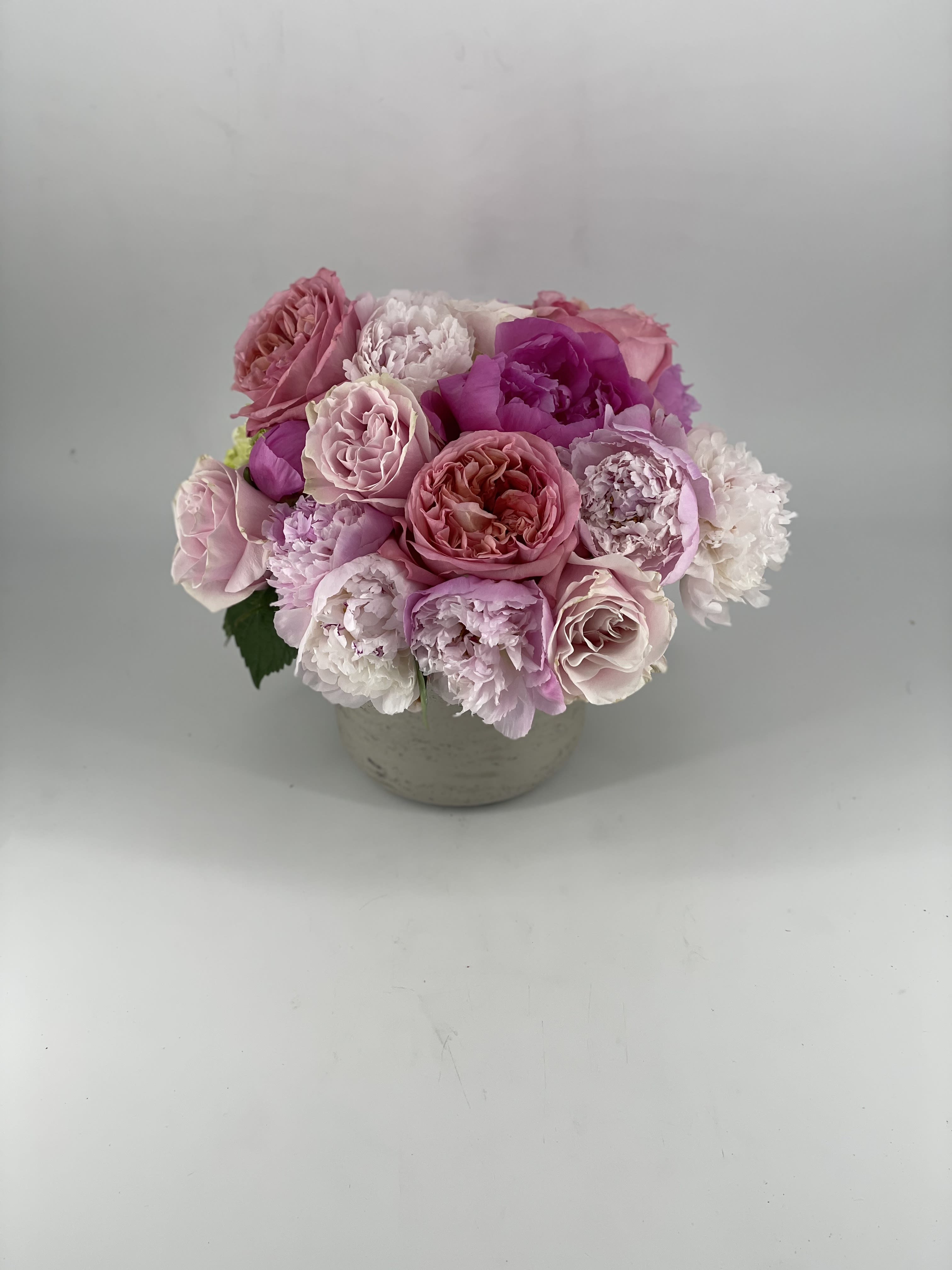 Gigi - This arrangement of beautiful pink tones pays tribute to my late Grandma, “GiGi,” who passed away many years ago — and way too soon — due to breast cancer. The simple elegance and beauty of these flowers honor the woman she was. The pink ribbon and theme represents breast cancer awareness and stands as a reminder to love and treasure our mothers, daughters, wives or sisters. This arrangement, created in our Concrete Rose Signature Vase, celebrates the strength and beauty of the women we love.