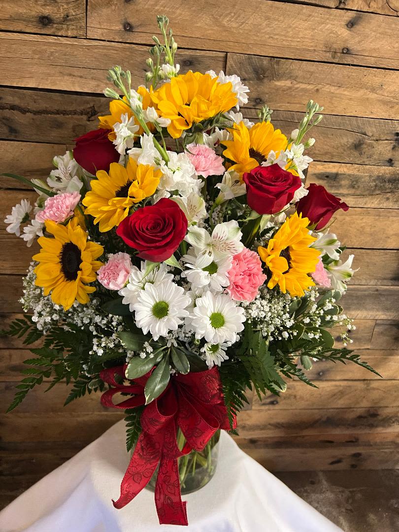 MI AMOR - ARRANGEMENT IN LARGE CYLINDER VASE WITH RED ROSES, SUNFLOWERS, STOCK, ALSTROEMERIA, DAISIES, CARNATIONS, MISC FILLER FLOWERS (FLOWER COLORS WILL VARY)   
