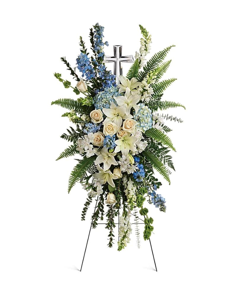 Eternal Grace Spray - Celebrate the eternal grace of a life well lived with this dramatic spray of peaceful white and blue blooms, crowned with a large crystal cross keepsake. This serene spray includes blue hydrangea,crème roses, white asiatic lilies, white alstroemeria, bells of Ireland, blue delphinium, white snapdragons, myrtle, sword fern, leatherleaf fern, spiral eucalyptus, and variegated pittorsporum. Delivered on a wire easel with a Crystal Cross Keepsake.