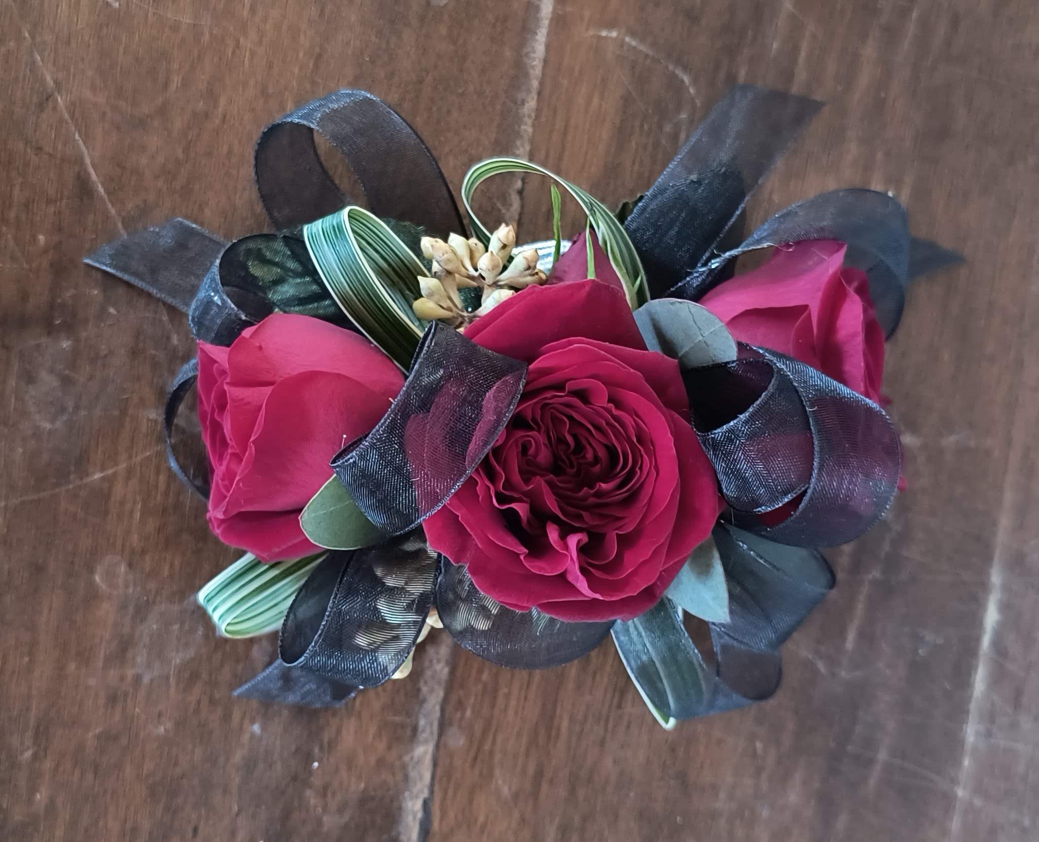 All Night Wrist Corsage - Delicate red spray rose blooms accented with black ribbon and assorted fresh greenery. Included is a throw away elastic wristlet. To dress it up some, change out the wristlet for pearl wristlet or a rhinestone one! Add gems for even more pizazz.