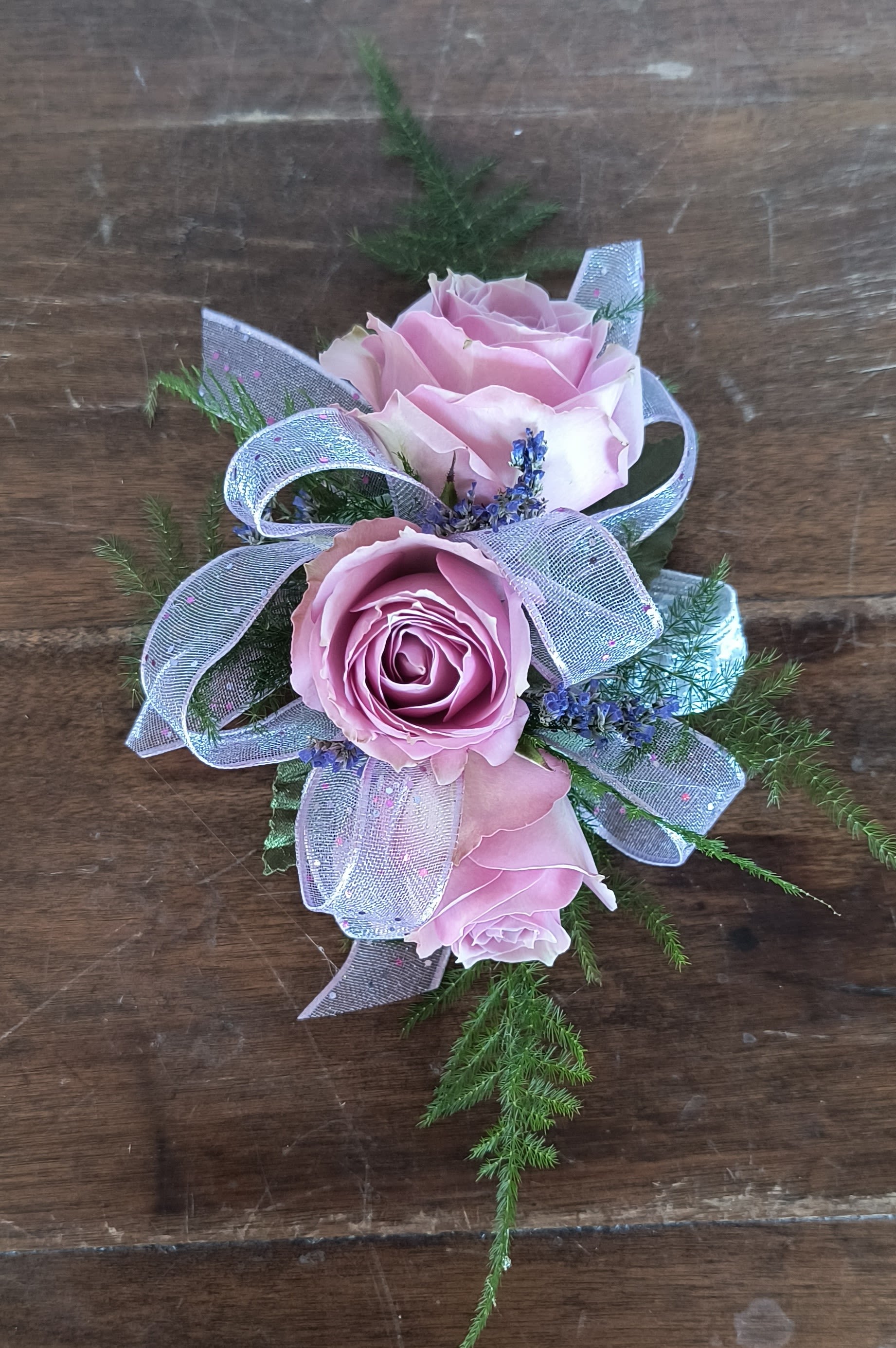 Lavender Rose Wrist Corsage - Cute as can be is this lavender/mauve spray rose wrist corsage with purple limonium filler flower and soft fern greens. Add as many accessories as you wish! *Included in this corsage is an elastic disposable wristlet.