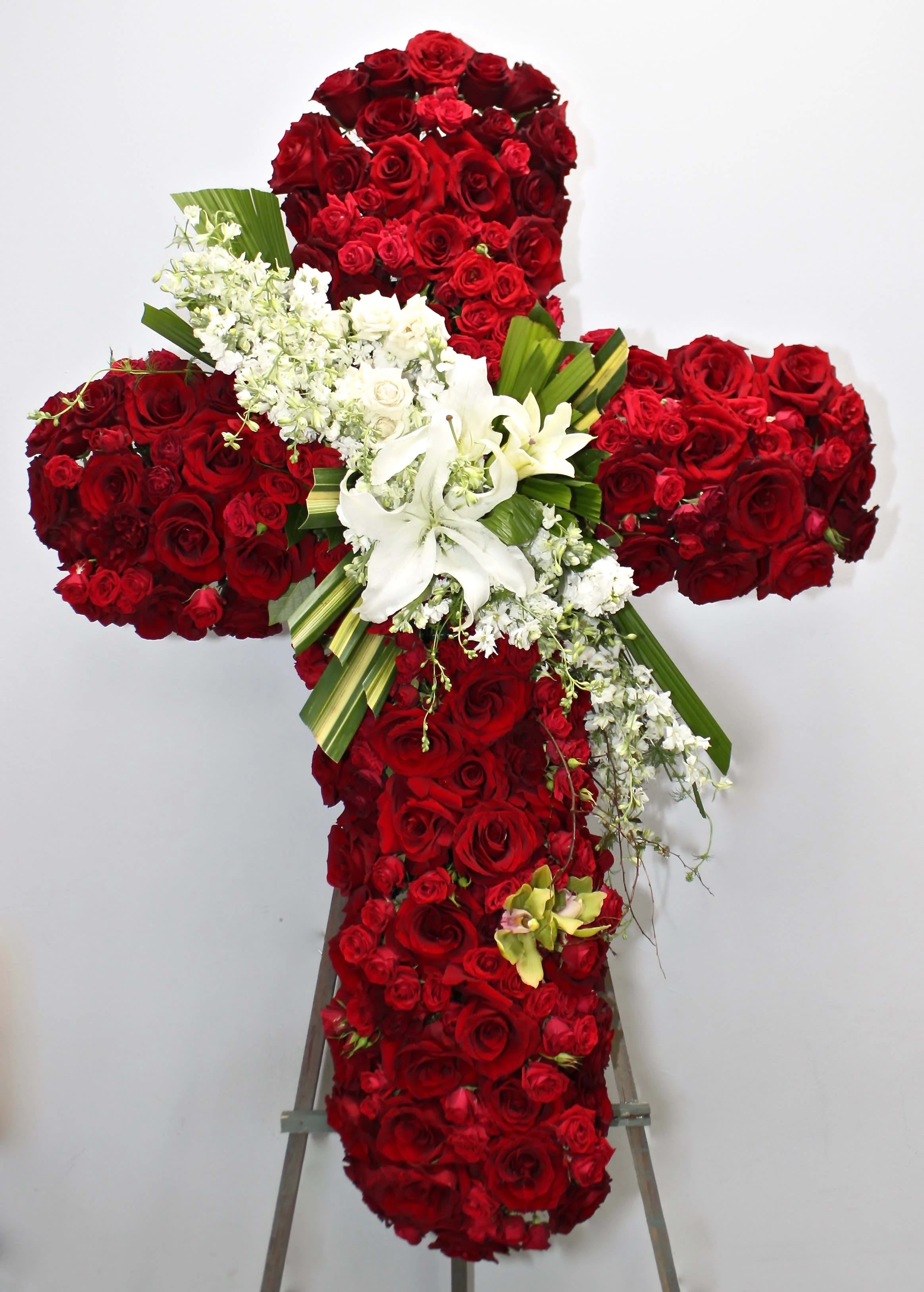 Red Rose Star Burst Cross  - This cross contains red roses of various sizes as well as a stargazer focal point. Seasonal greens and florals are also included in this cross.     We include easel, printed banner and delivery (some fees may apply). An additional banner can be added for $15.    Standard size is 30'', deluxe is 36'', and premium is 42''.