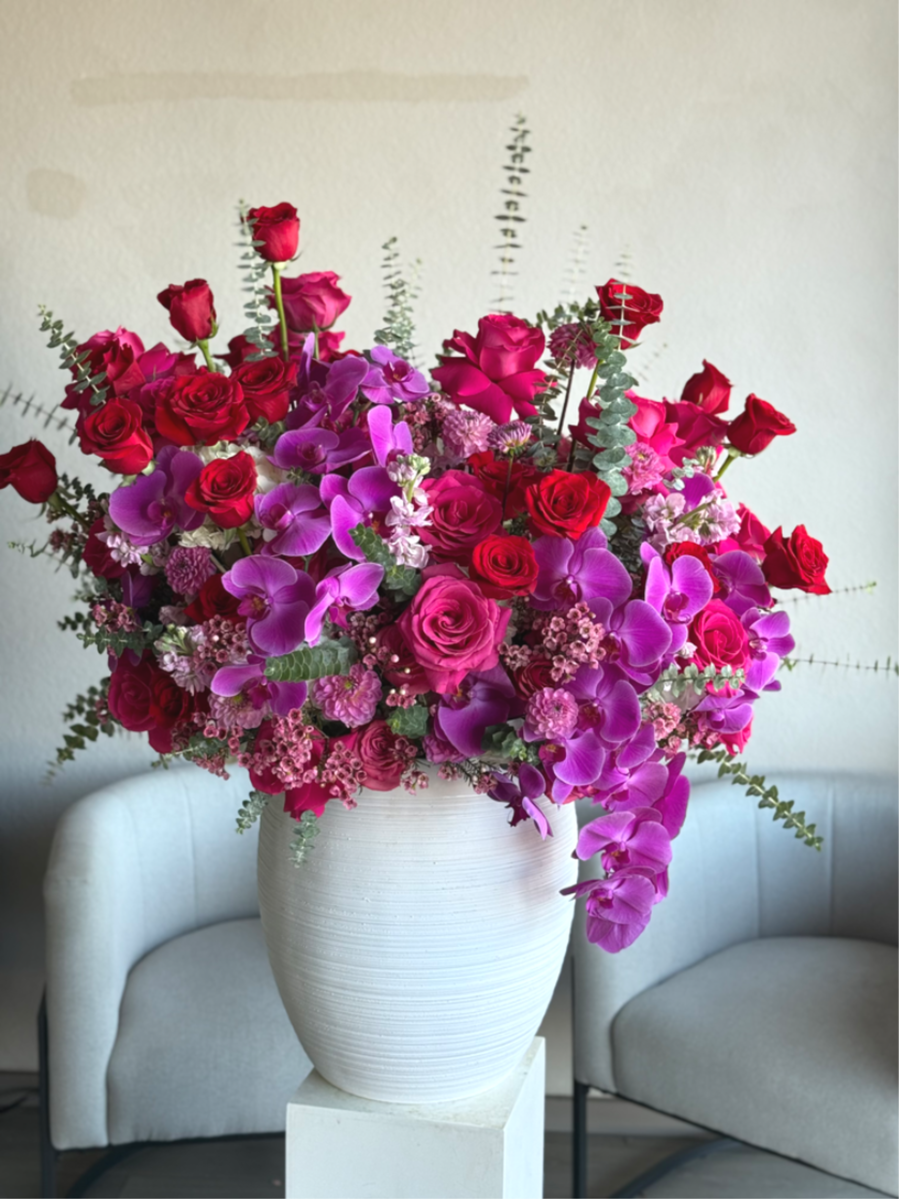 Rouge &amp; Fuchsia - Grand Arrangement - Rouge &amp; Fuchsia – Grand Arrangement — A breathtaking, statement-making arrangement designed in a luxurious white vase, featuring a bold mix of rich red and vibrant hot pink roses. Finished with premium orchids for an elevated, couture look, this grand design is the perfect choice for Valentine’s Day, anniversaries, or any moment that deserves an unforgettable gesture of love.