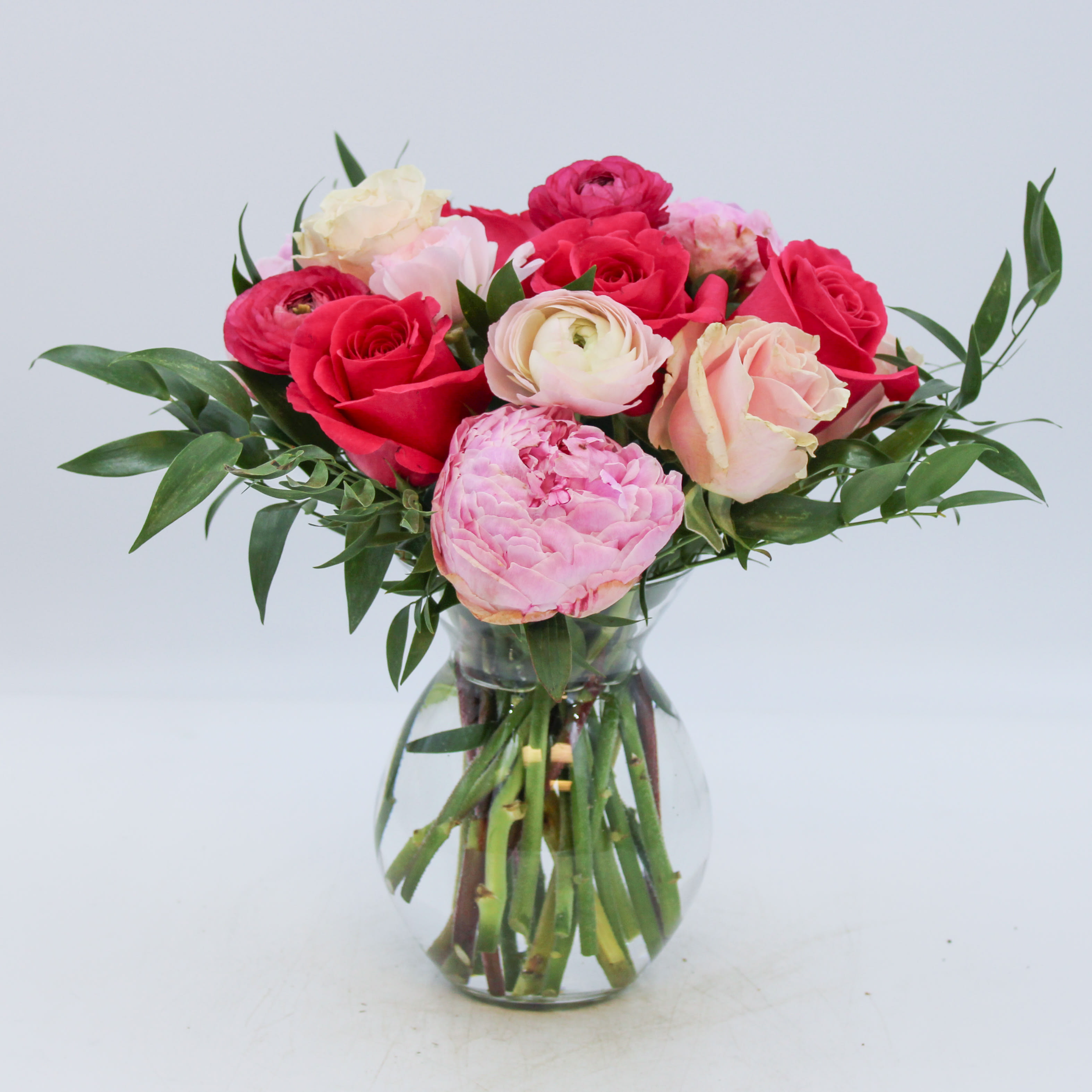 Amour - Amour is an adorable and luxurious design with only premium flowers including Peonies, Hot Pink and Blush Roses, Hot Pink and Blush Ranunculus, along with Italian Ruscus. Amour is approximately 9 inches wide and 11.5 inches tall. *If Peonies are unavailable, we will substitute with Garden Roses.  