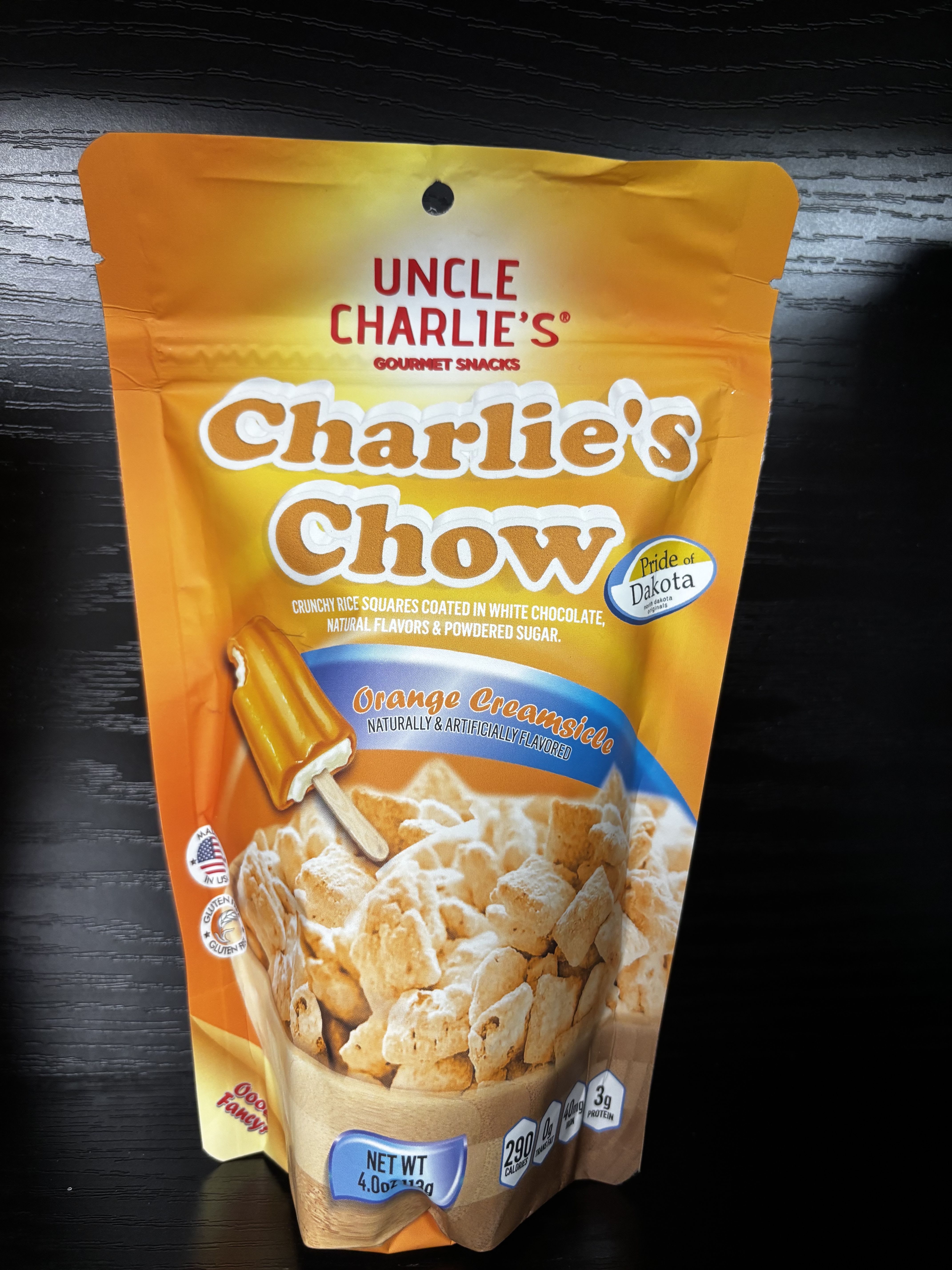 Charlie’s Chow – Orange Creamsicle - A nostalgic favorite with a sweet, creamy twist! Charlie’s Chow Orange Creamsicle blends crunchy rice squares with smooth white chocolate and bright orange-vanilla flavor, inspired by the classic frozen treat. Finished with a light dusting of powdered sugar, this cheerful snack is creamy, citrusy, and perfectly balanced. Ideal for summer displays, gift baskets, road trips, or anyone who loves a fun, retro-inspired treat.
