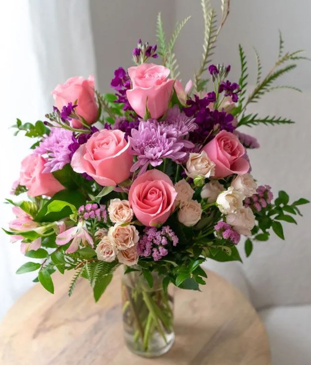 Sweet Thing - A soft and romantic arrangement featuring a curated mix of blush pinks, soft purples, and fresh greenery. Designed with seasonal blooms that may vary while maintaining the same color palette and overall style. Artfully arranged in a clear glass vase for a light, effortless look. Perfect for celebrating love, milestones, or simply brightening any space!