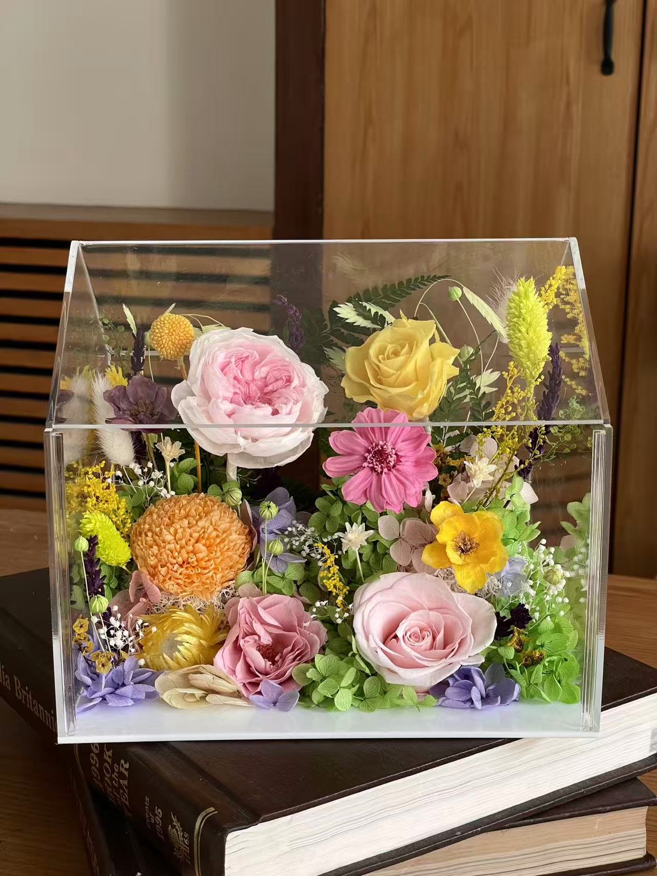 Preserved Flower Acrylic Display Box - A vibrant preserved flower arrangement featuring a harmonious mix of roses, garden-style blooms, and delicate botanical accents, artfully arranged inside a clear acrylic display box. This piece captures the beauty of a blooming garden in a modern, collectible form.  Crafted with real preserved flowers, this arrangement is designed to last 1–5 years with proper care. No watering or maintenance required—simply display and enjoy its lasting beauty.  Perfect for home décor, desks, shelves, or as a thoughtful gift for birthdays, anniversaries, and special occasions. Each arrangement is handmade; slight variations make every piece unique.
