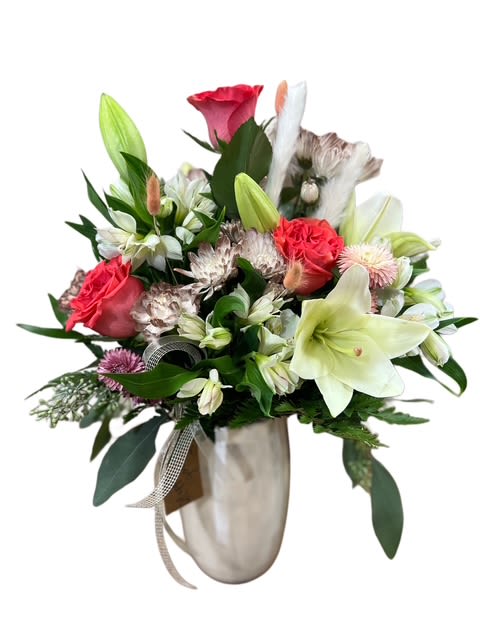 Blushing Garden Vase - A soft and cheerful arrangement perfect for celebrating life’s little moments. Featuring coral roses, mums and carnations sprayed with a hint of gold,  creamy lilies, and delicate accent blooms with fresh greenery, this bouquet radiates natural charm and warmth. Designed in a neutral vase and tied with a simple ribbon and tag, it’s ideal for birthdays, anniversaries, or to brighten someone’s day with a touch of garden-fresh beauty.
